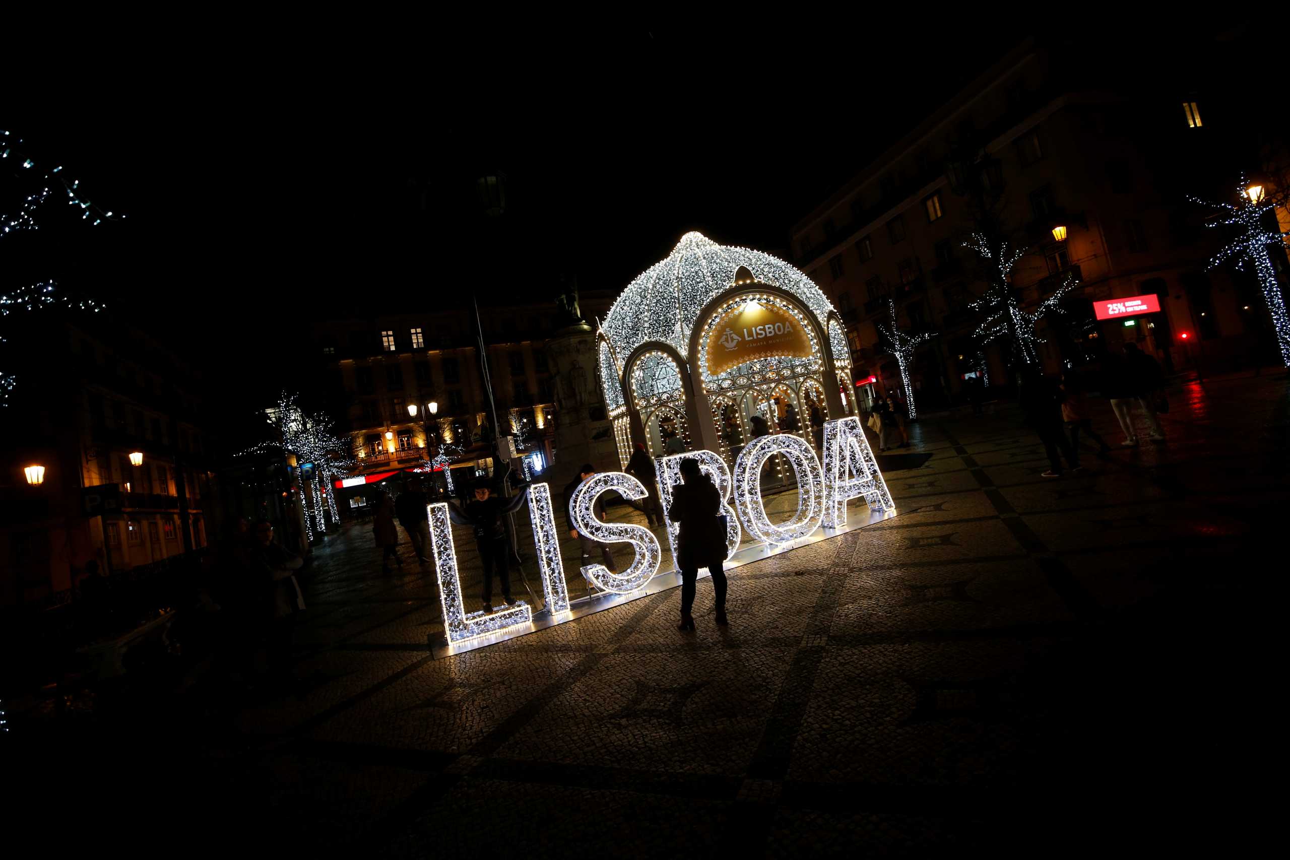 People walk and take pictures near Christmas decorations during the coronavirus disease (COVID-19) pandemic, in downtown Lisbon, Portugal, December 16, 2020. REUTERS