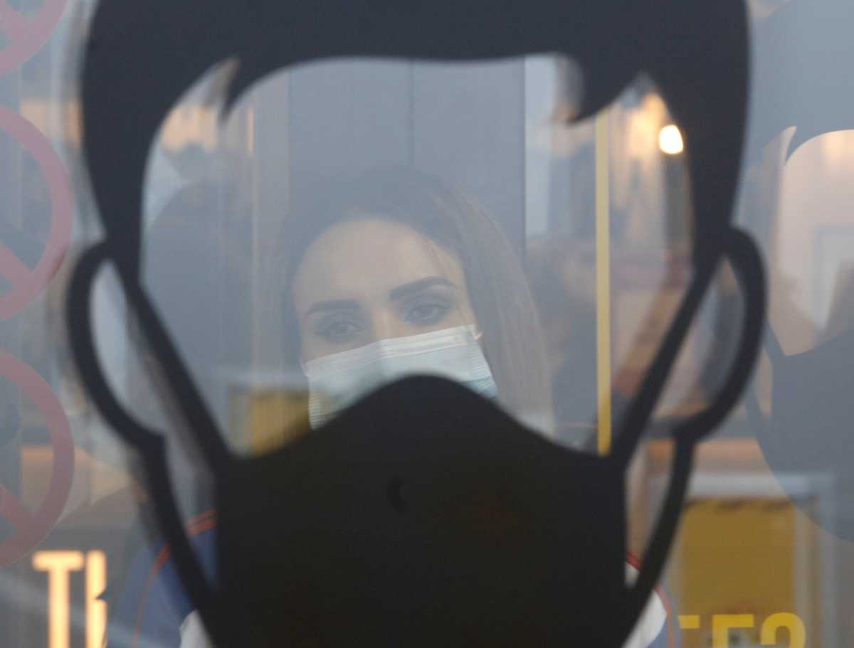 A woman is seen behind a sign requesting to use protective face masks amid the coronavirus disease (COVID 19) outbreak in Stavropol, Russia December 1, 2020. REUTERS