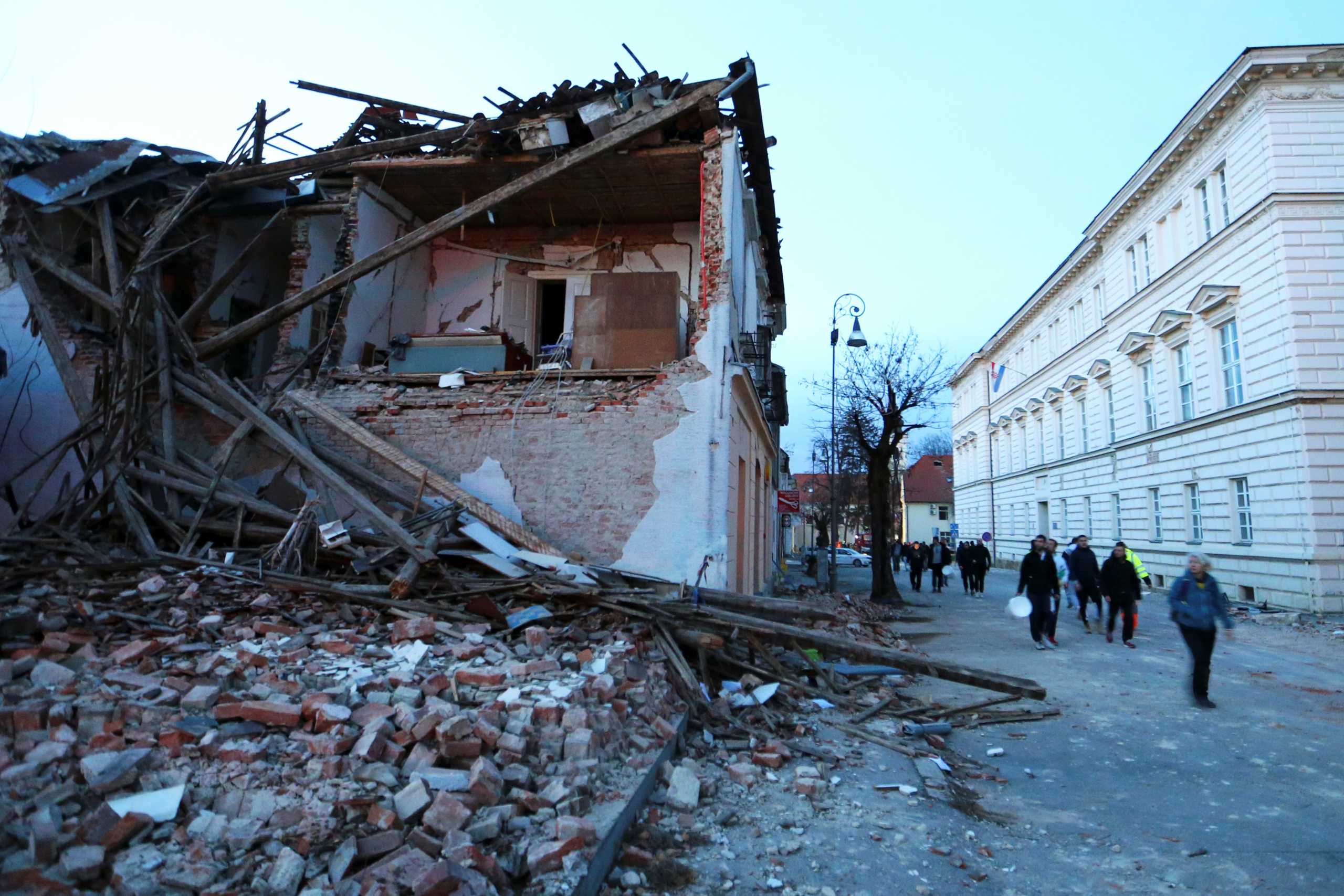 People walk past a collapsed building after an earthquake, in Petrinja, Croatia December 29, 2020. REUTERS