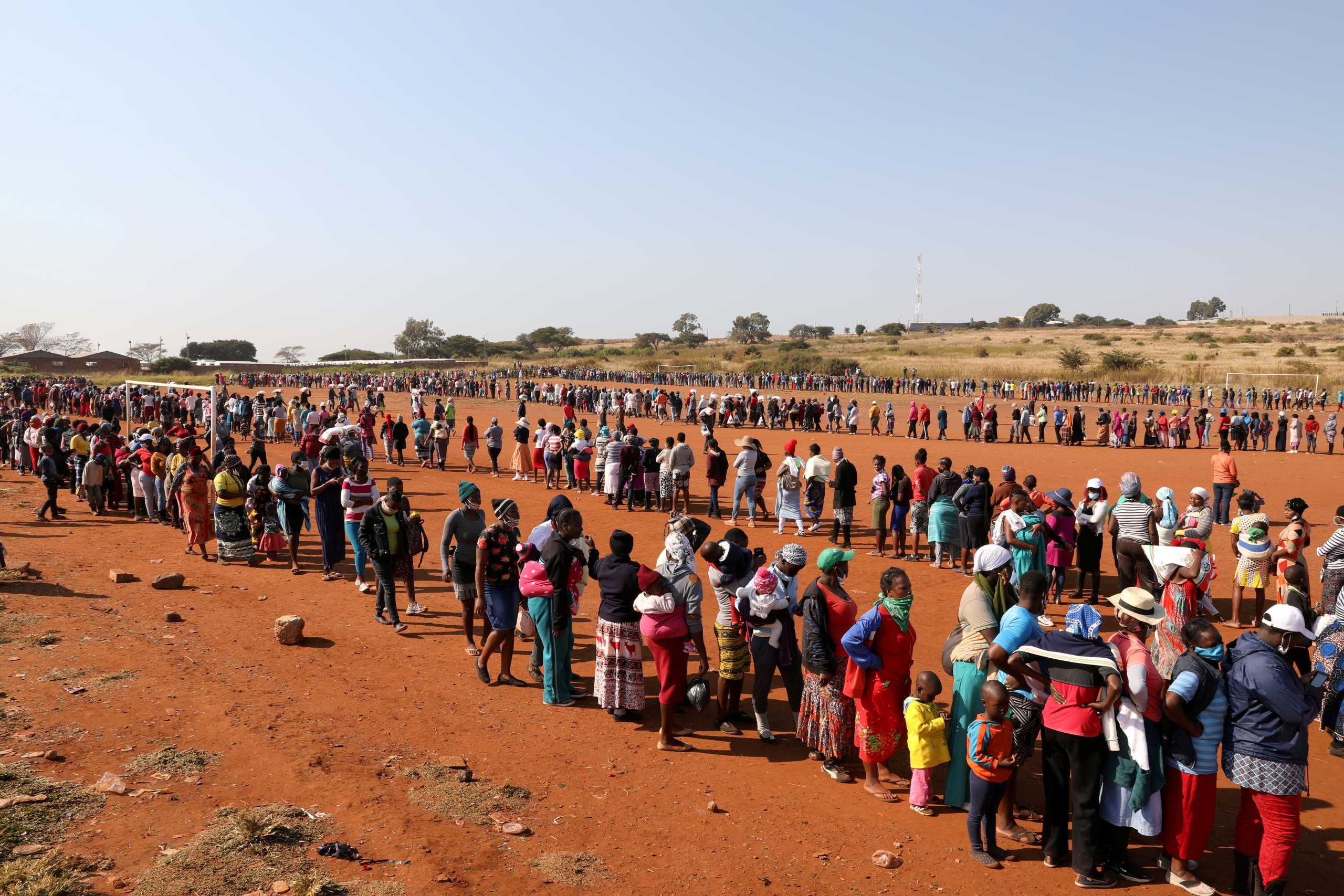 People stand in a queue to receive food aid, during the coronavirus disease (COVID-19) outbreak at the Itireleng informal settlement, near Laudium suburb in Pretoria, South Africa, May 20, 2020. REUTERS