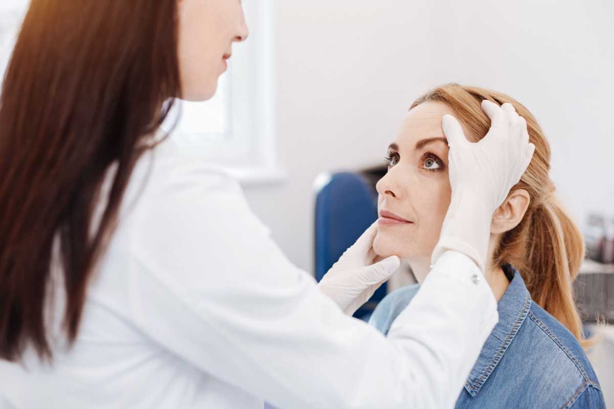 Female patient. Nice pleasant attractive woman sitting and looking at her doctor while being in the doctors office
