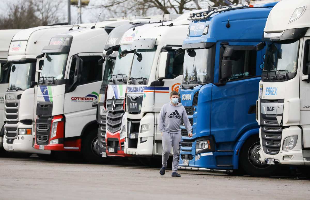 A driver wearing a face mask walks past lorries at Ashford International Truck Stop, as EU countries impose a travel ban from the UK following the coronavirus disease (COVID-19) outbreak, in Ashford, Britain December 22, 2020. REUTERS