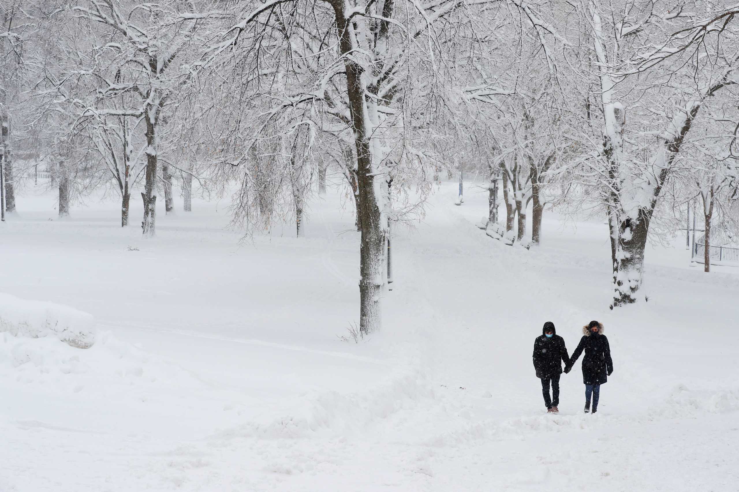 A couple walks through the Boston Common during a snow storm in Boston, Massachusetts, U.S., December 17, 2020.  REUTERS