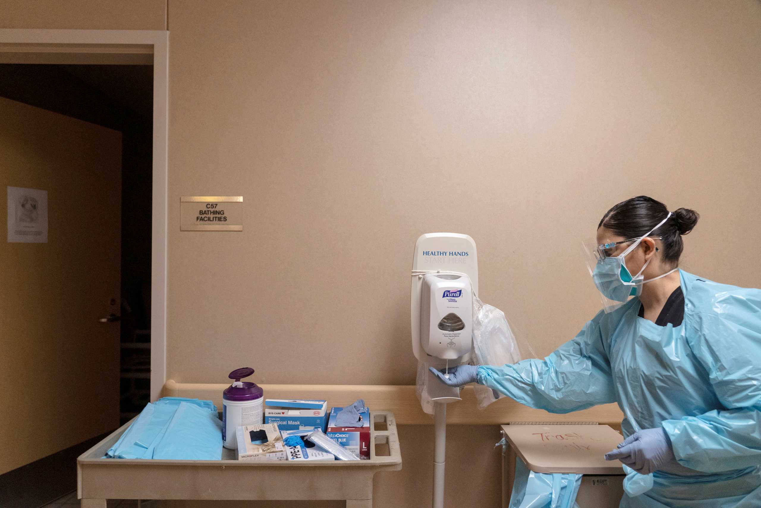 Healthcare worker Maria Meza wears personal protective equipments as she uses a hand sanitizer dispenser after treating a coronavirus disease (COVID-19) positive patient at Medical Arts Hospital in Lamesa, Texas, U.S., December 17, 2020.  Picture taken December 17, 2020. REUTERS