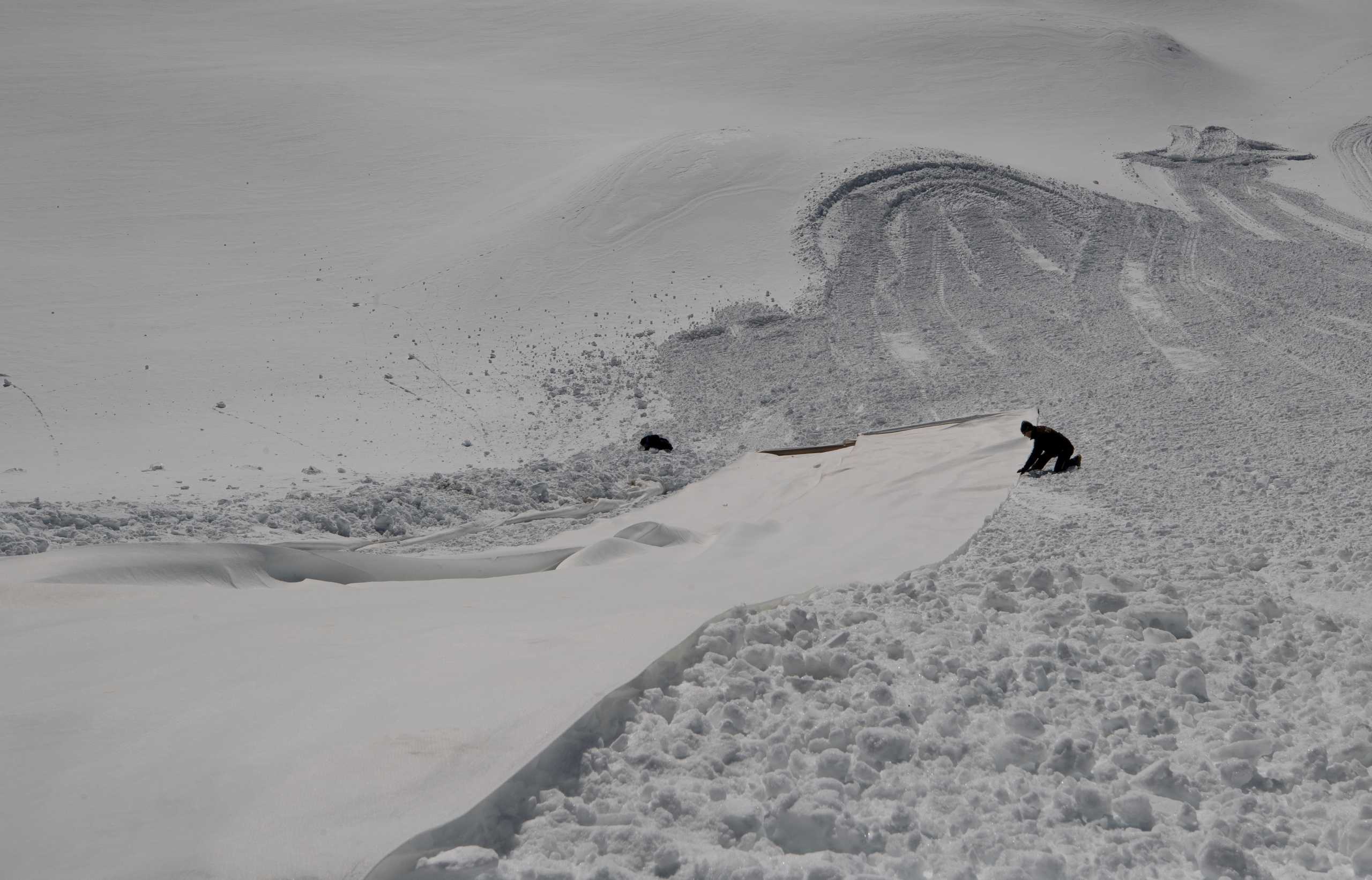 FILE PHOTO: A worker adjusts a Vlies fabric to cover the snow of a glacier at Stubaier glacier ski resort near Neustift im Stubaital, Austria, May 7, 2020. Picture taken May 7, 2020. REUTERS
