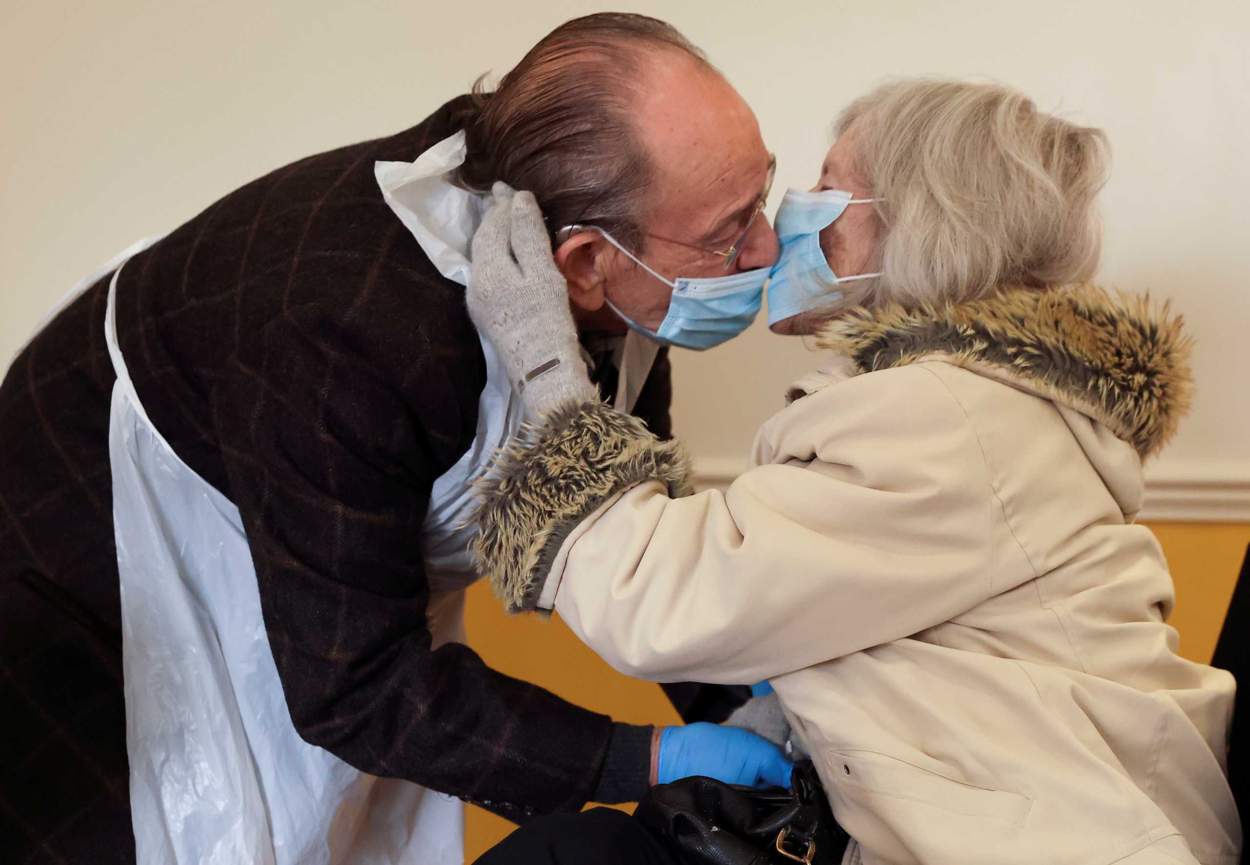 Bob Underhill, 84, and his wife Patricia, 82, suffering from Alzheimer's, kiss through a face mask as they are allowed to visit with physical contact for the first time at The Chiswick Nursing Centre, which has introduced a coronavirus disease (COVID-19) test with results ready in thirty minutes, in London, Britain December 2, 2020.  REUTERS