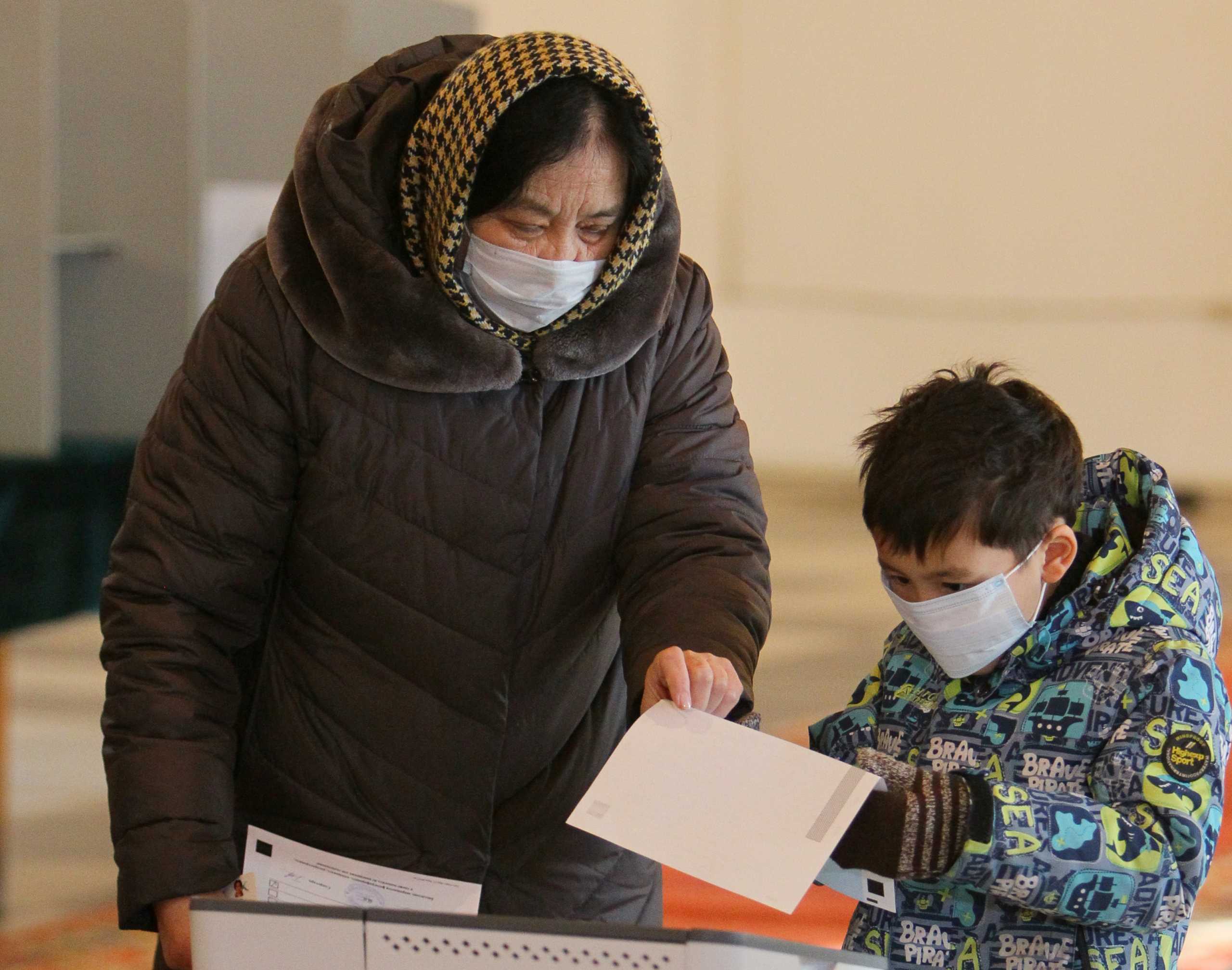 A woman and a child cast a ballot at a polling station during a presidential election and constitutional referendum in Bishkek, Kyrgyzstan January 10, 2021. REUTERS