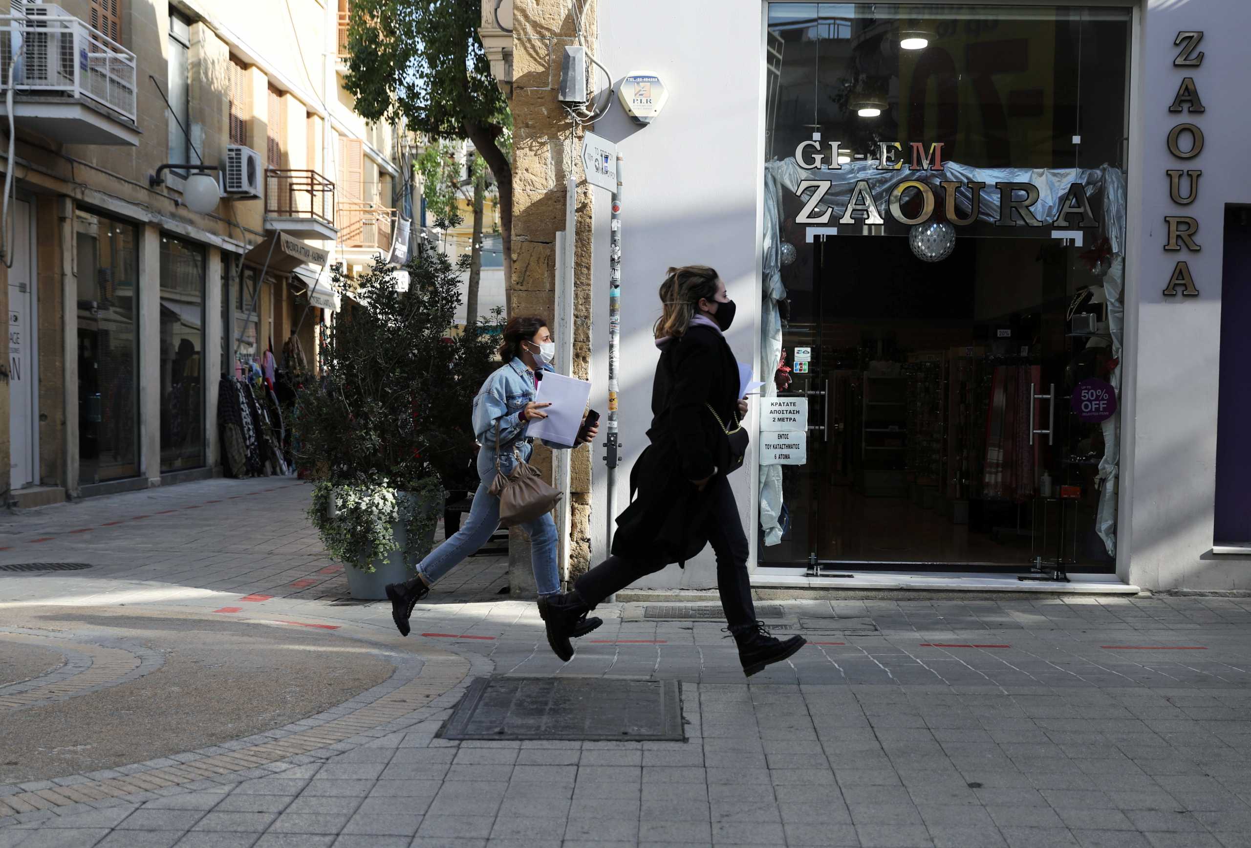 Two women wearing protective masks run in Ledra Street, a main shopping street, amid the coronavirus disease (COVID-19) pandemic in Nicosia, Cyprus January 8, 2021. REUTERS
