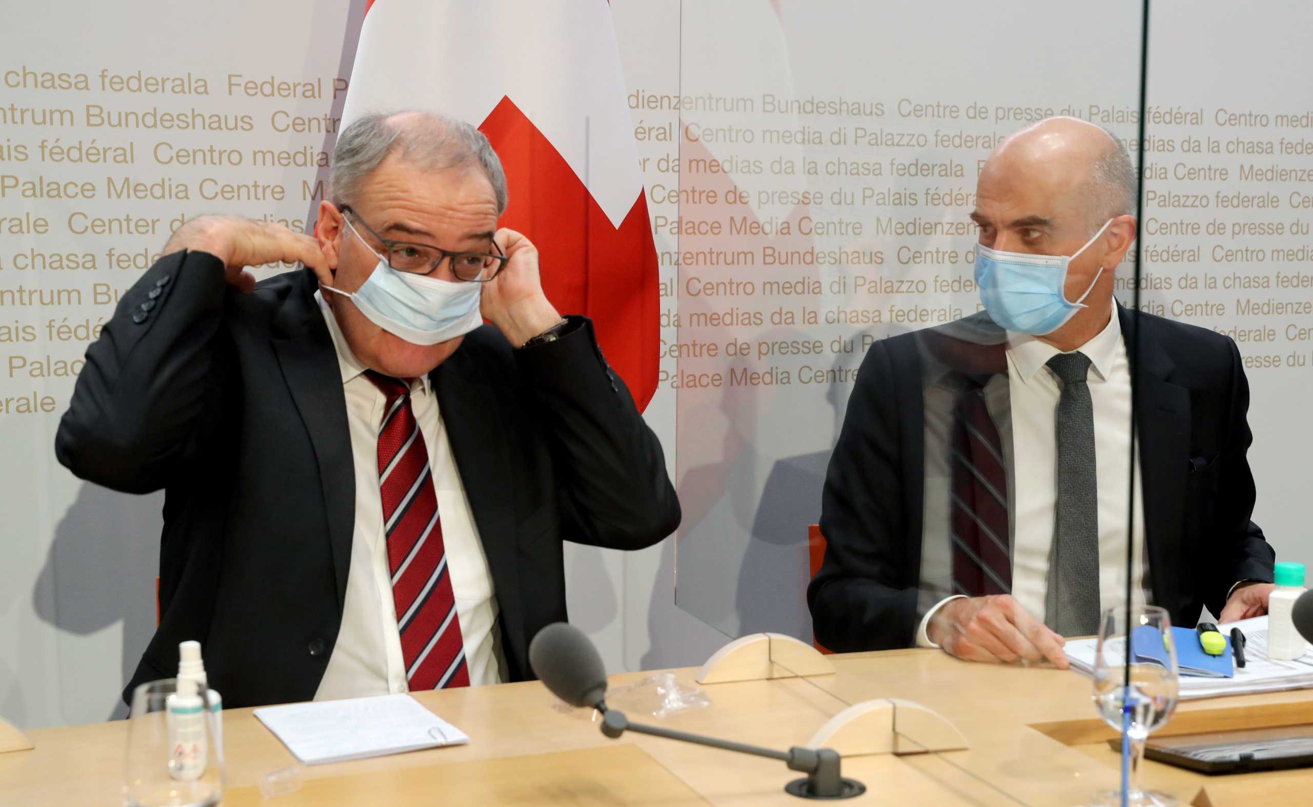 Swiss President Guy Parmelin adjusts his protective mask next to Swiss Interior Minister Alain Berset after a news conference, as the spread of the coronavirus disease (COVID-19) continues, in Bern, Switzerland January 13, 2021. REUTERS