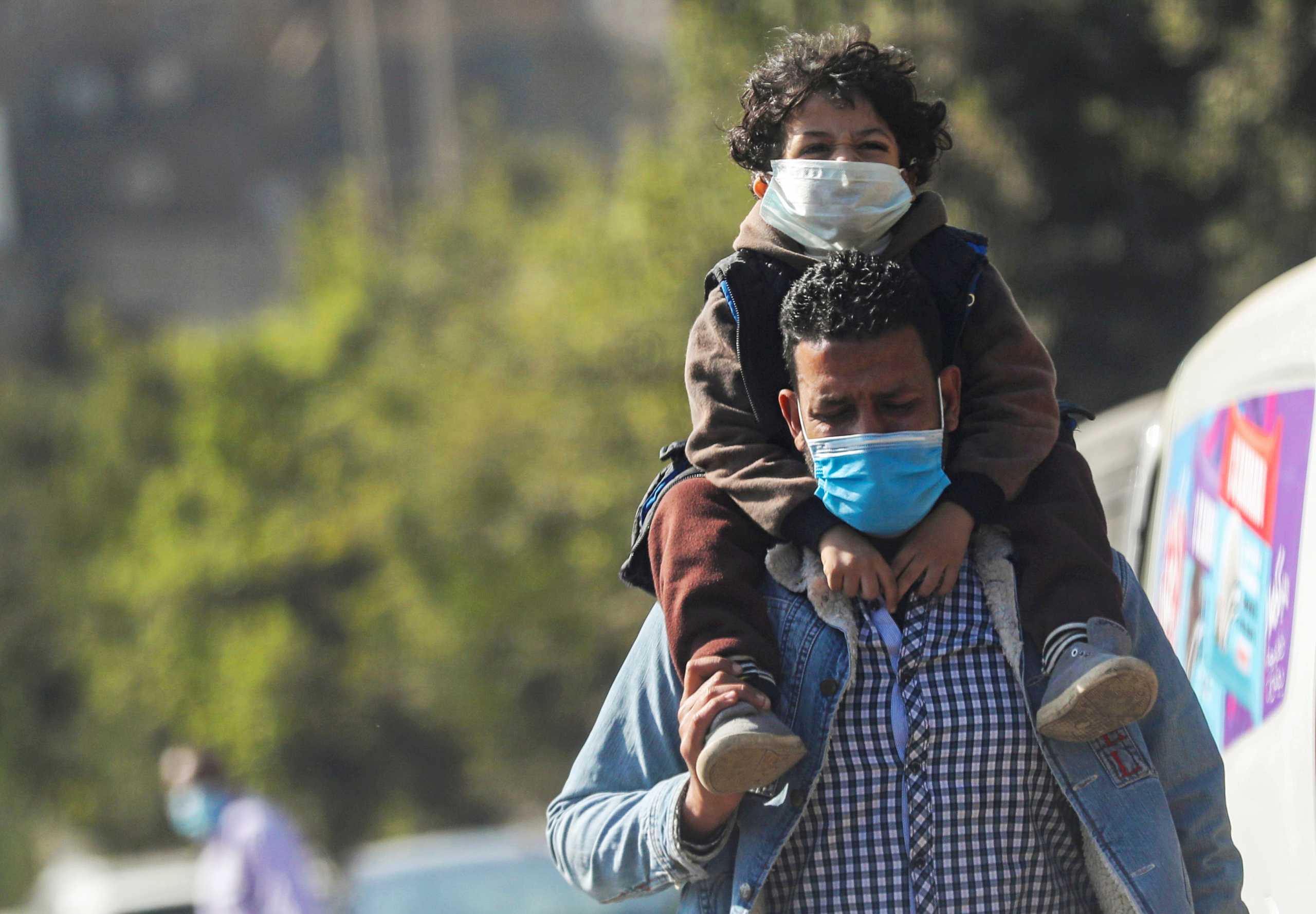 A man wearing a face mask carries his son on the street, amid the coronavirus disease (COVID-19) outbreak, in Cairo, Egypt January 11, 2021. REUTERS