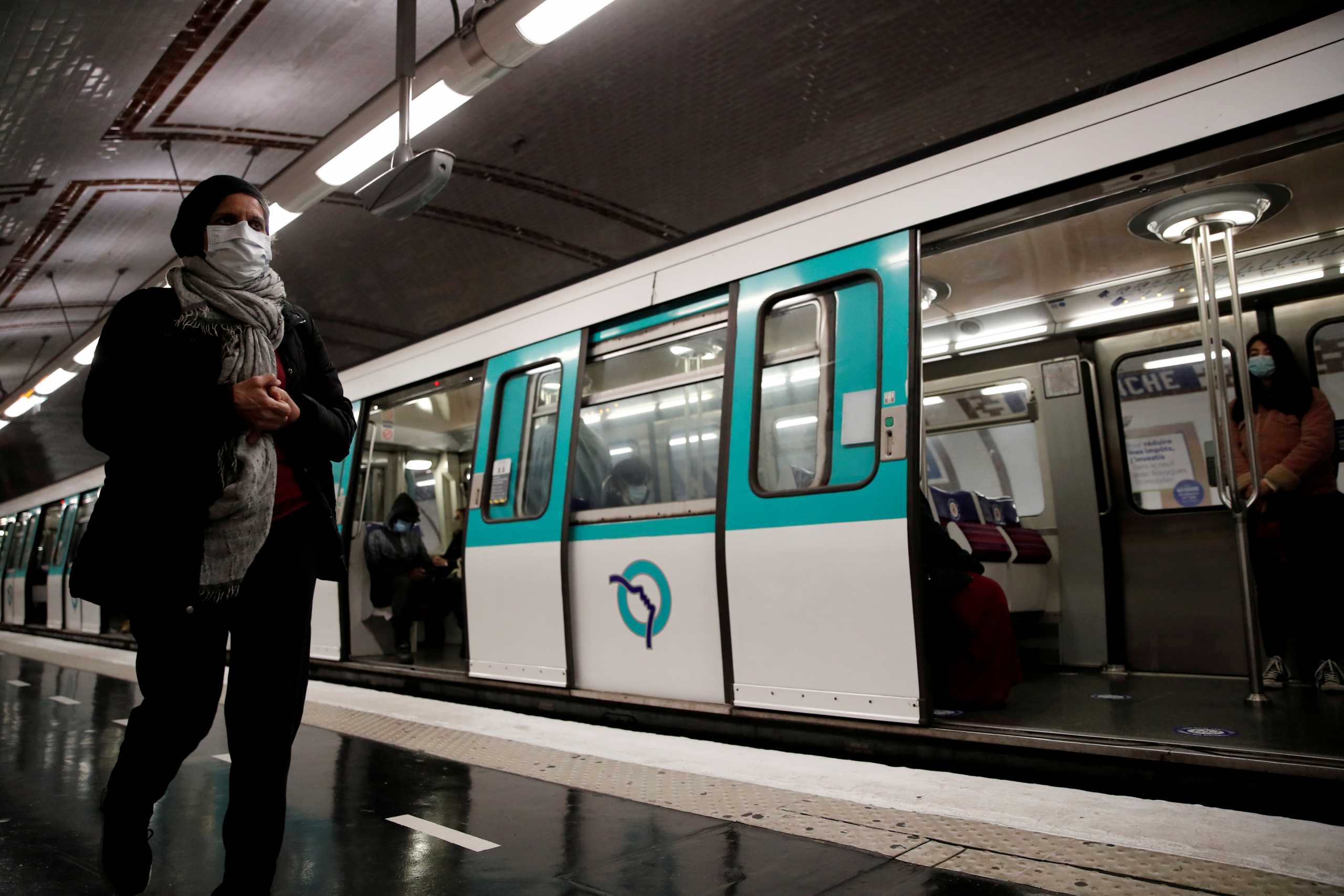FILE PHOTO: People wearing protective face masks walk on a platform at a metro station of Paris transport network (RATP) in Paris as France softens its strict lockdown rules during the outbreak of the coronavirus disease (COVID-19) in France, May 11, 2020.  REUTERS