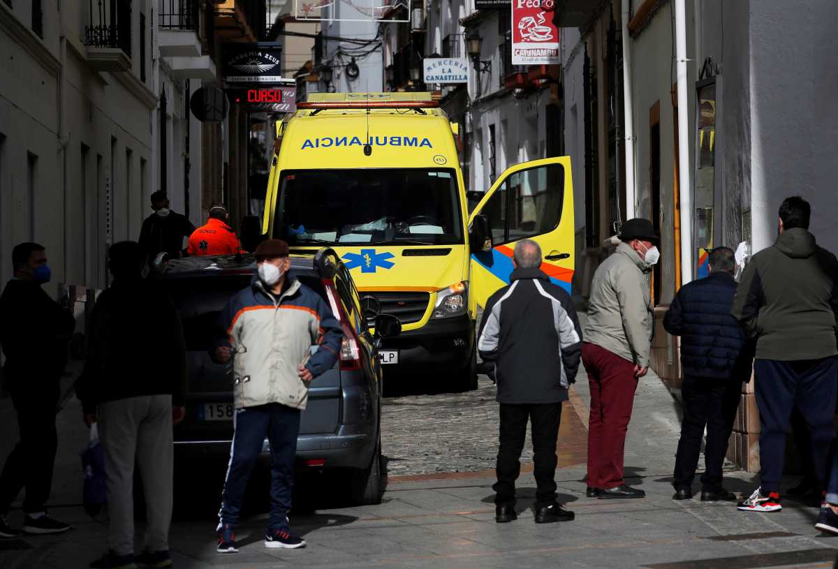 People stand near an ambulance as healthcare workers treat a patient suffering from the coronavirus disease (COVID-19) during a home visit, amid the coronavirus disease (COVID-19) outbreak, in Ronda, southern Spain January 23, 2021. REUTERS