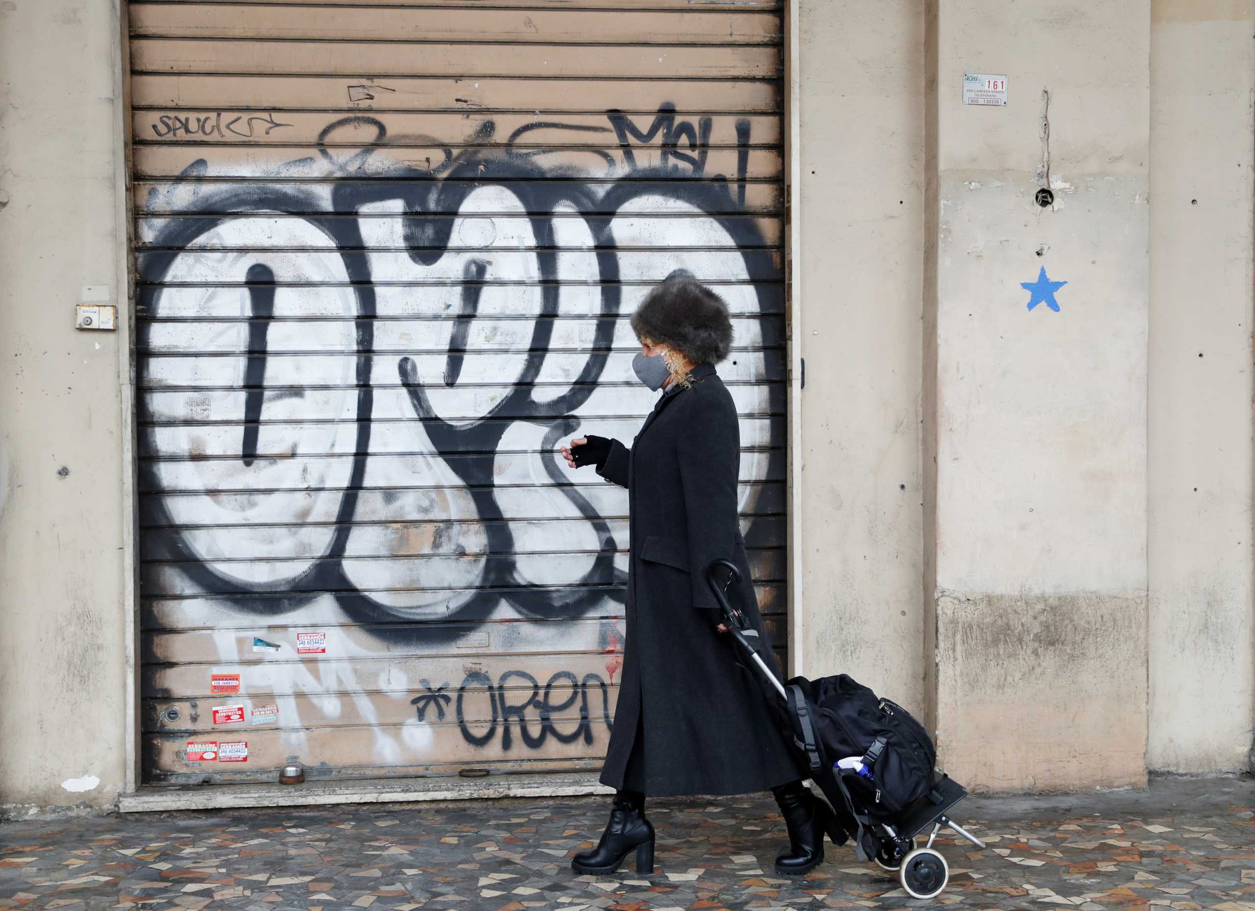 A woman walks past a closed shop as the spread of the coronavirus disease (COVID-19) continues, in Rome, Italy January 22, 2021. REUTERS
