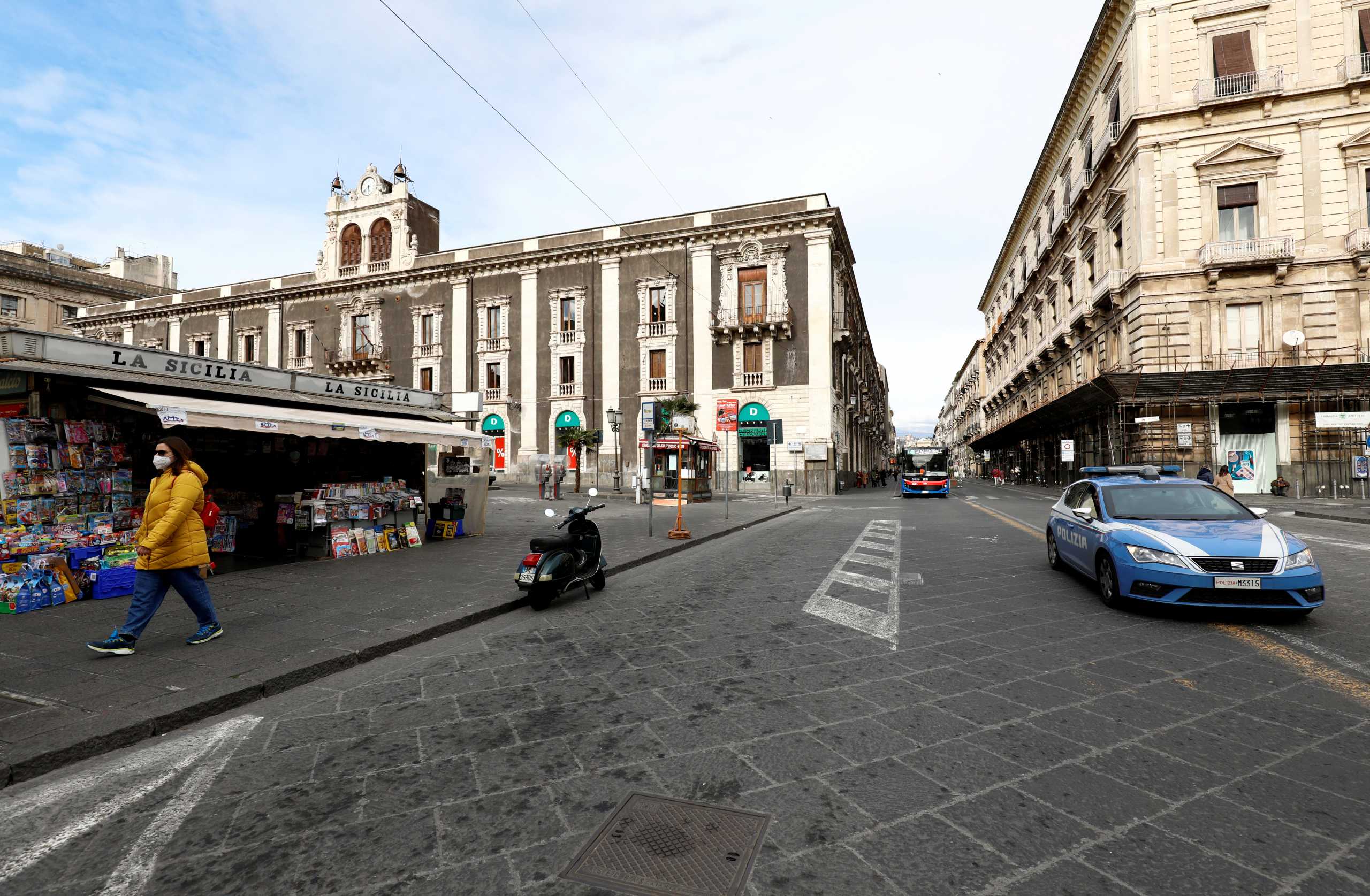 FILE PHOTO: A person wearing a face mask walks past a newsstand in Catania, Italy, January 17, 2021. REUTERS
