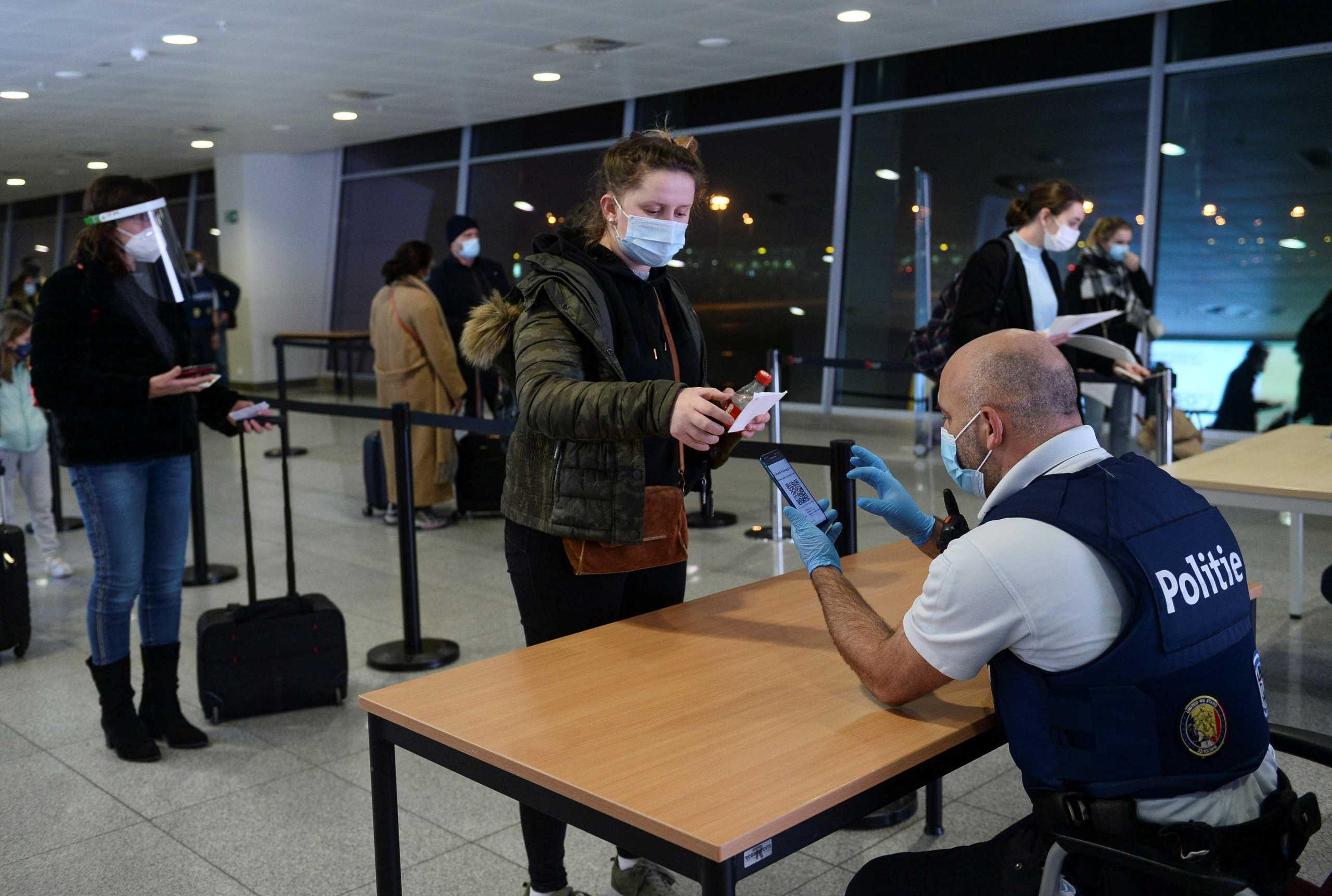 A Belgian police officer checks the papers of a passenger at the terminal of Brussels airport due to the new rules imposed by the government as the coronavirus disease (COVID-19) outbreak continues in Brussels, Belgium January 2, 2021. REUTERS