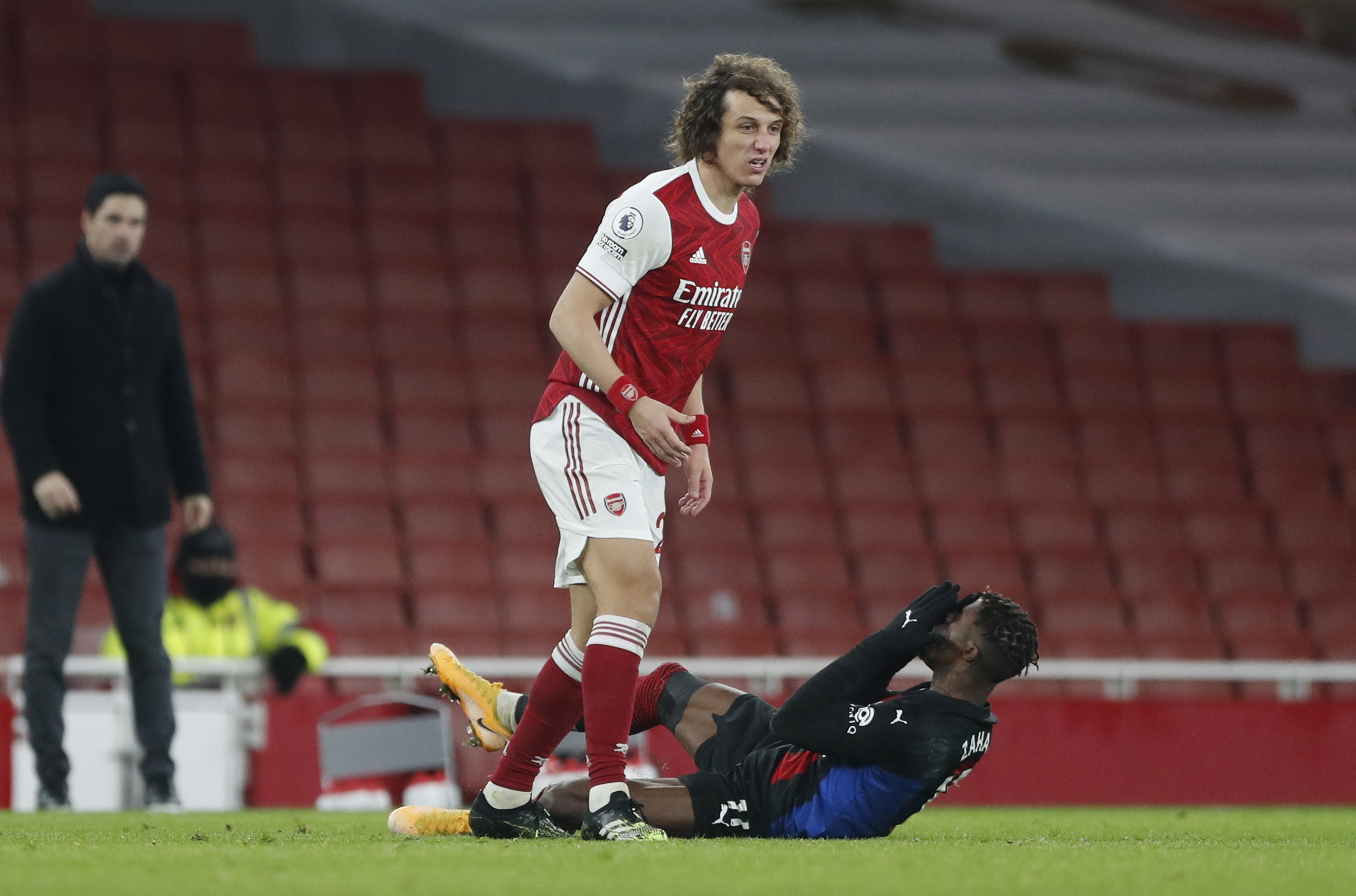 Soccer Football - Premier League - Arsenal v Crystal Palace - Emirates Stadium, London, Britain - January 14, 2021  Crystal Palace's Wilfried Zaha reacts on the ground alongside Arsenal's David Luiz Pool via REUTERS