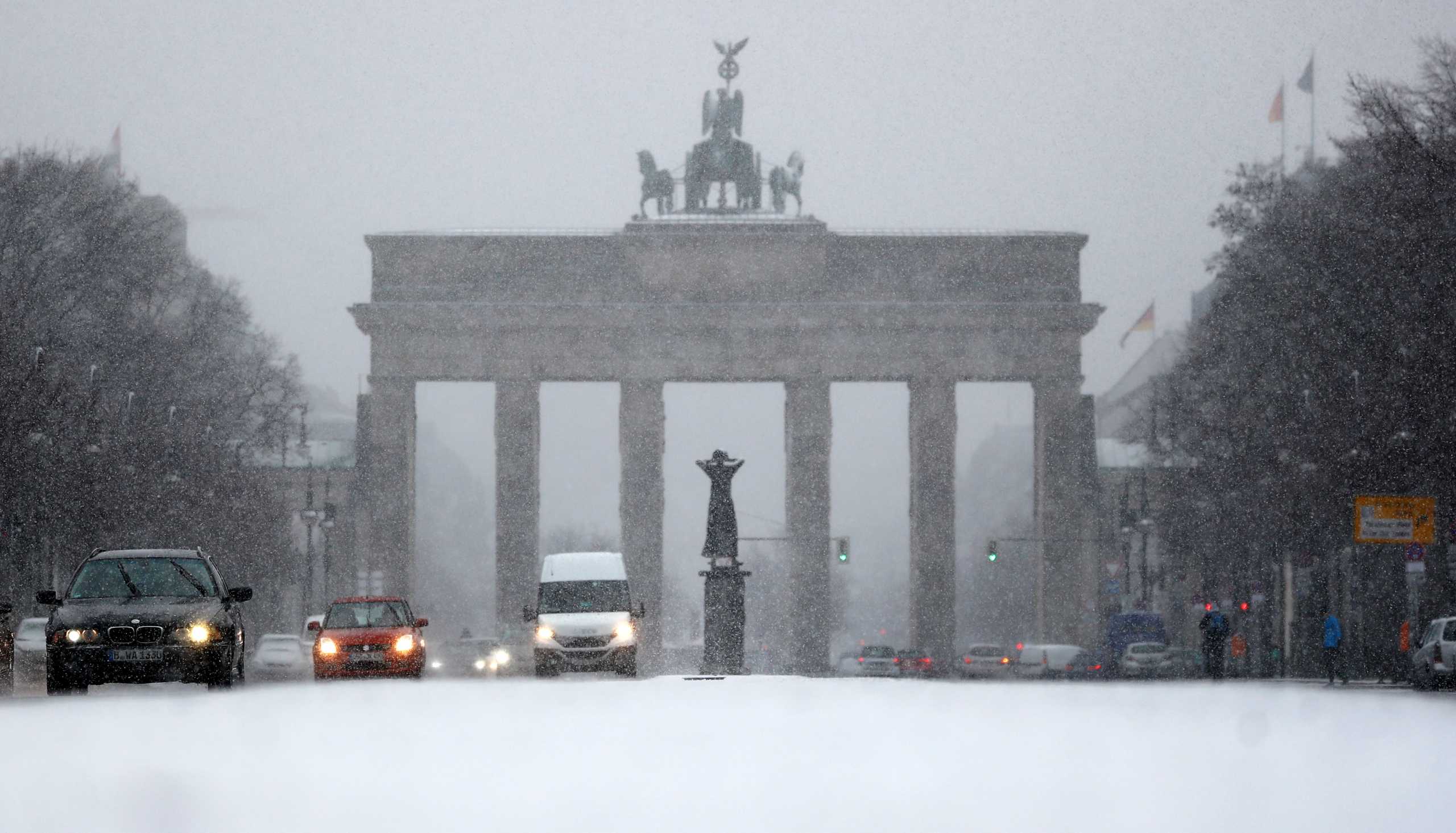 Cars pass in front of Brandenburg Gate during snowfall in Berlin, Germany, January 19, 2021. REUTERS