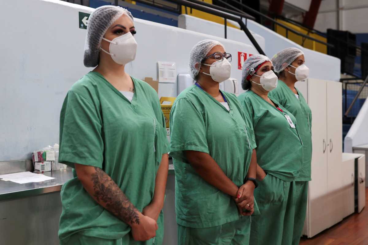 Medical personnel stand in a minute of silence for the victims of the coronavirus disease (COVID-19) as they work during the New Year at a field hospital set up at a sports gym in Santo Andre, Sao Paulo state, Brazil, January 1, 2021. REUTERS
