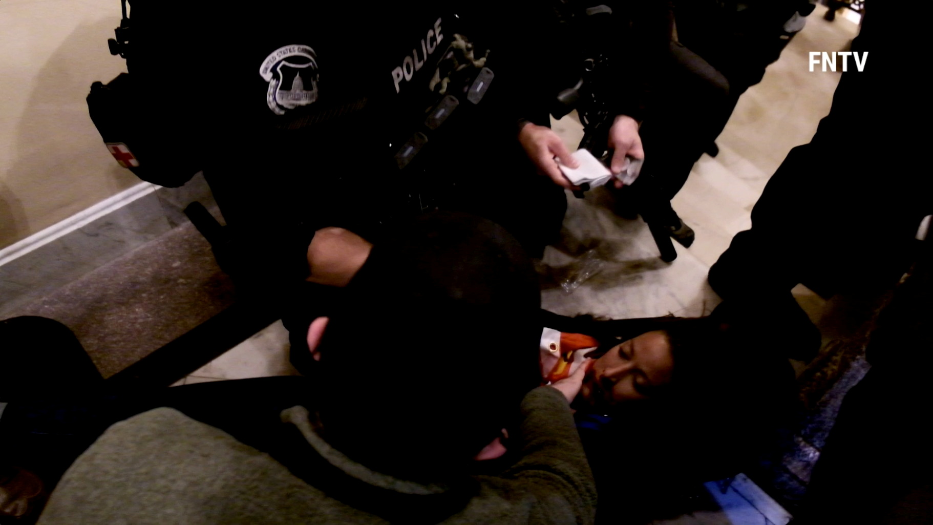 SENSITIVE MATERIAL. THIS IMAGE MAY OFFEND OR DISTURB People and police help a woman, who was shot, as she lies on the floor, after supporters of U.S. President Donald Trump entered the Capitol building in Washington DC, U.S. , in this still frame obtained from social media video January 6, 2021.  FREEDOMNEWS.TV