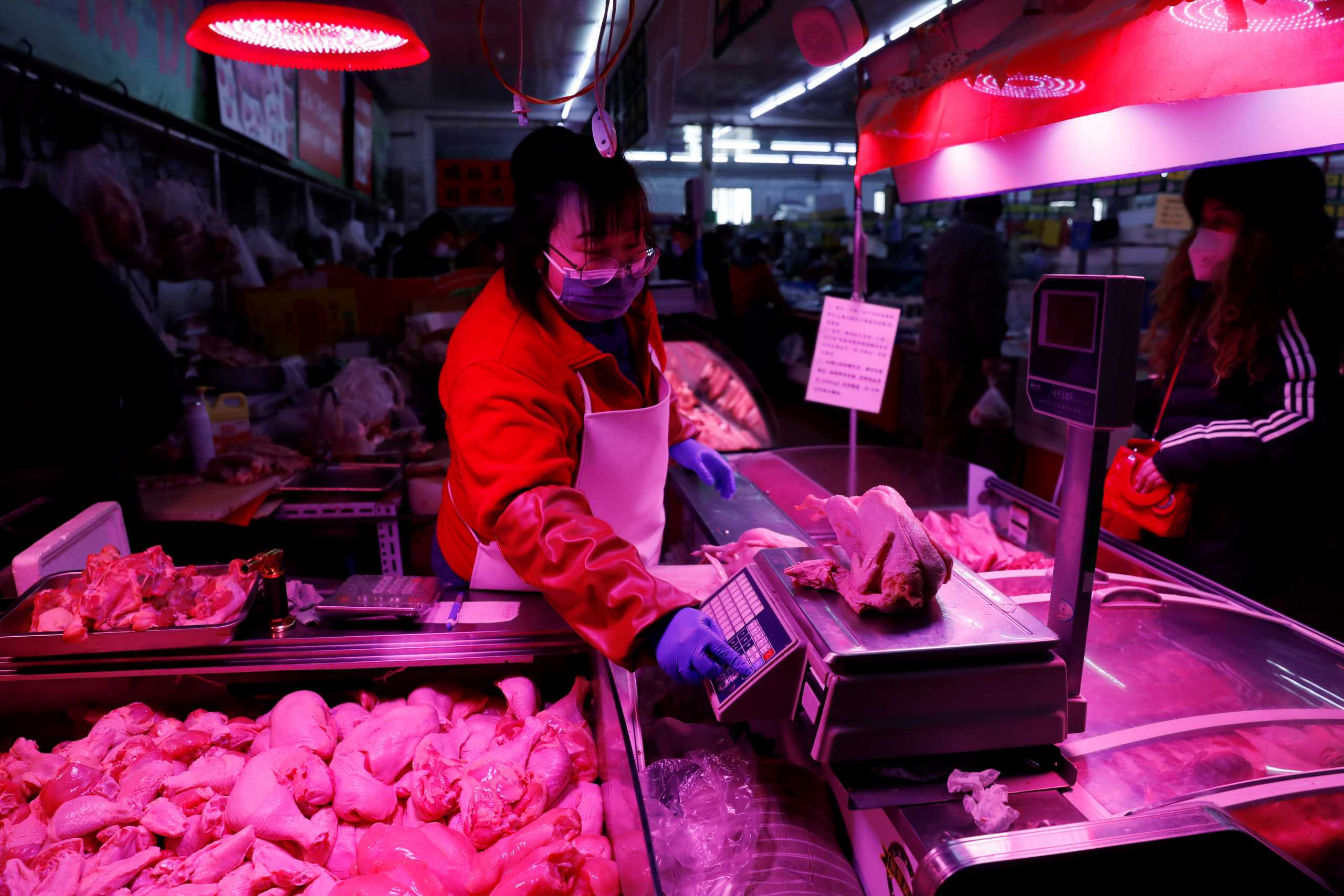 A vendor wearing a face mask following the coronavirus disease (COVID-19) outbreak weighs a chicken at her stall inside a market in Beijing, China, January 15, 2021. Picture taken January 15, 2021. REUTERS