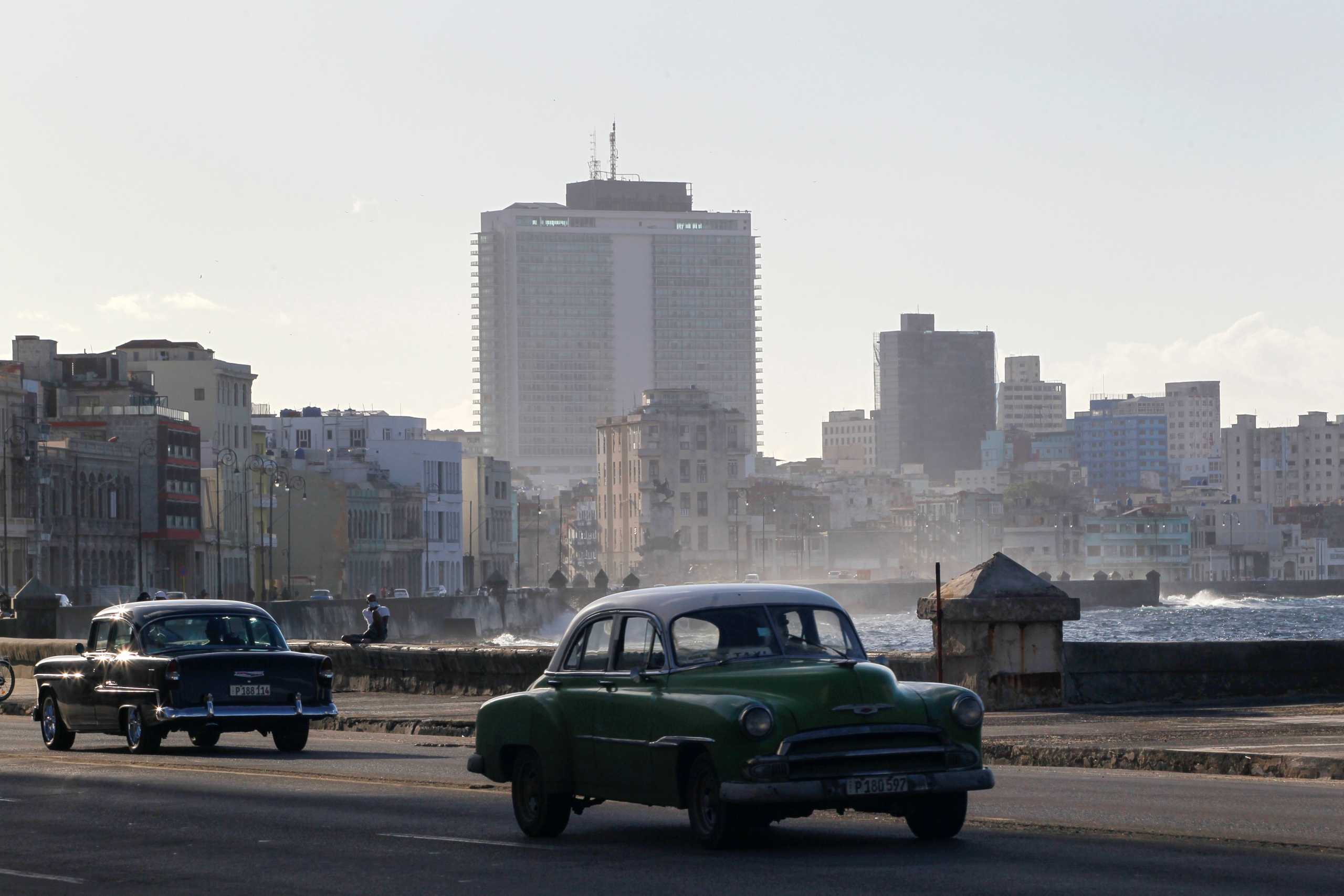 Vintage cars drive on the seafront boulevard El Malecon in Havana, Cuba, December 29, 2020. REUTERS
