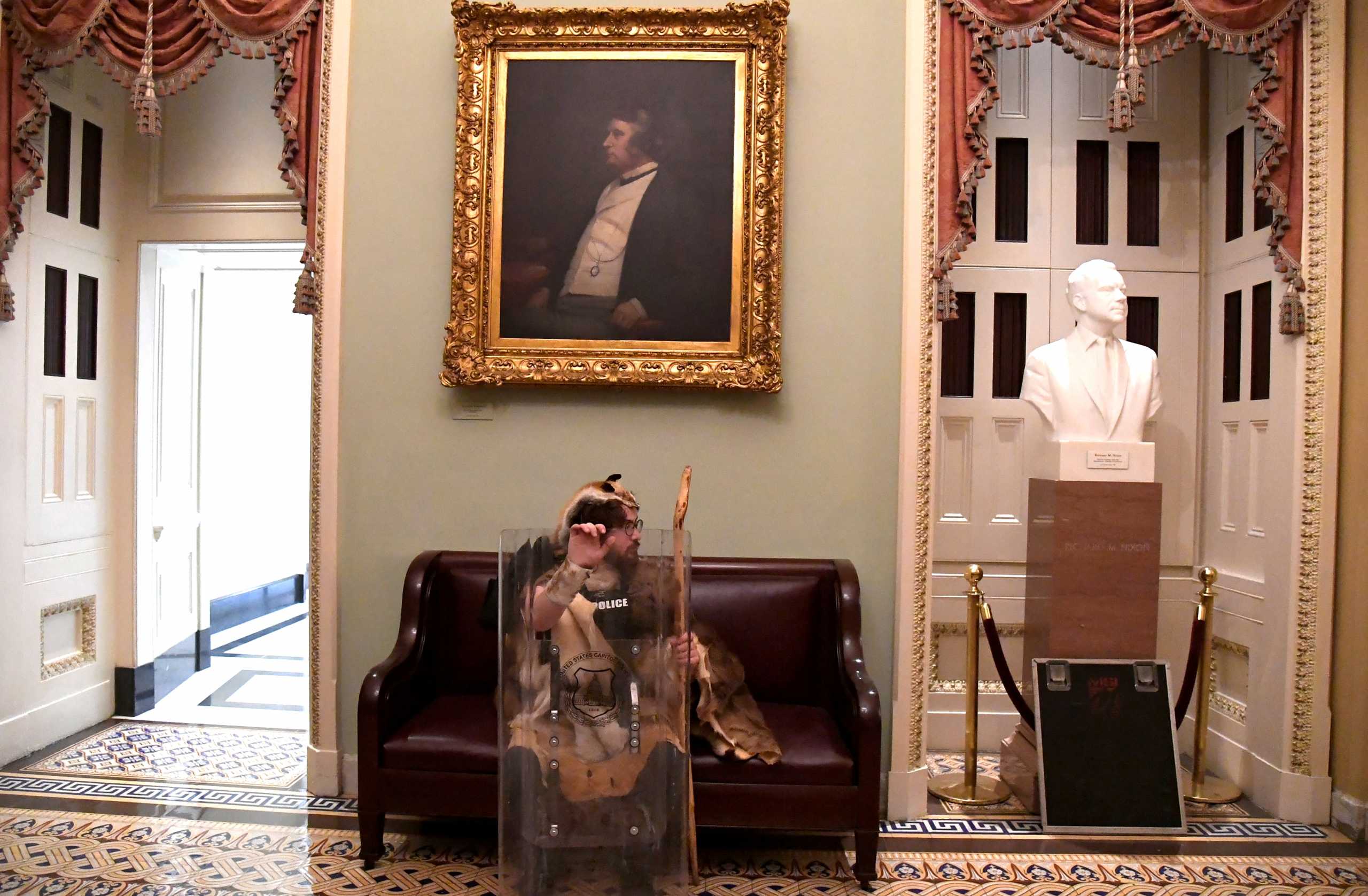 A supporter of President Donald Trump takes a seat away from the action on the second floor of the U.S. Capitol near the entrance to the Senate after breaching security defenses, in Washington, U.S., January 6, 2021.         REUTERS