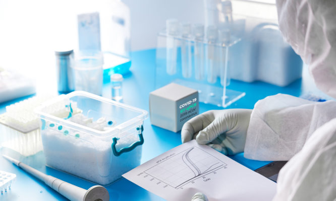 SARS-COV-2 nucleic acids diagnostics kit. Epidemiologist in protective suit, mask and glasses performs and analyzes results of pcr tests detecting SARS-nCoV-2 virus, cause of Covid-19 viral pneumonia.