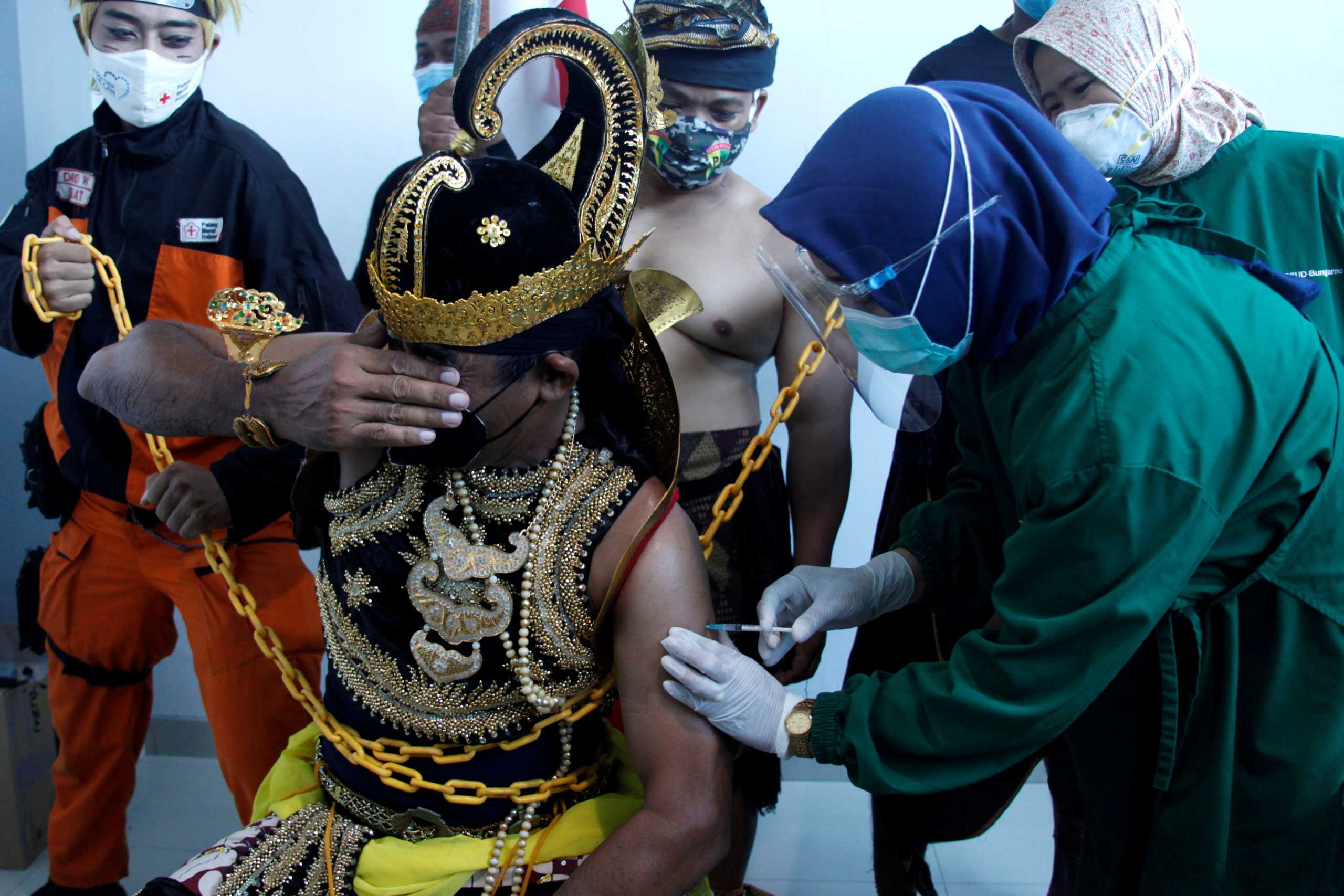 An Indonesian healthcare worker injects a dose of Sinovac's vaccine to a man dressed in Indonesia's traditional human puppet costume known as 'Wayang', as Indonesia drives mass vaccination for the coronavirus disease (COVID-19), at a hospital in Solo, Central Java province, Indonesia, January 22, 2021 in this photo taken by Antara Foto.  Antara Foto