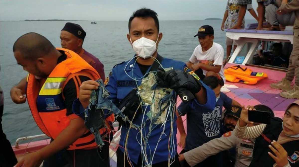 A member of the rescue team looking for an Indonesian plane that lost contact after taking off from the capital Jakarta holds suspected debris, at sea, January 9, 2021, in this picture obtained from social media. INSTAGRAM @HUMASJAKFIRE