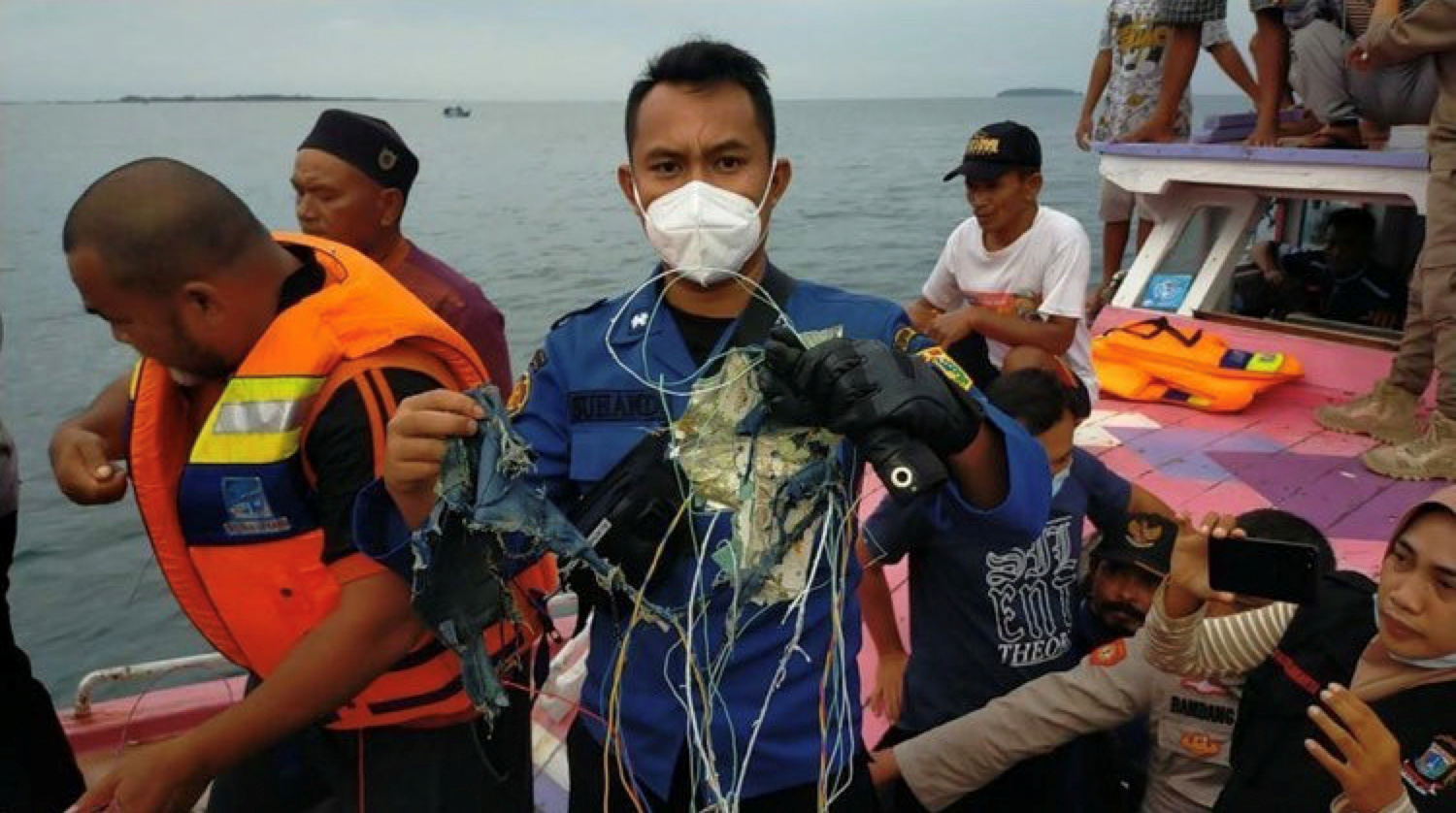 A member of the rescue team looking for an Indonesian plane that lost contact after taking off from the capital Jakarta holds suspected debris, at sea, January 9, 2021, in this picture obtained from social media. INSTAGRAM @HUMASJAKFIRE