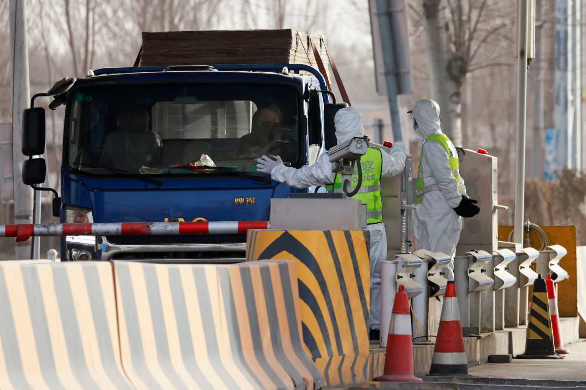 Police officers in PPE stop a car coming from Hebei province at a checkpoint, following the coronavirus disease (COVID-19) outbreak, on the outskirts of Beijing, China January 12, 2021. REUTERS