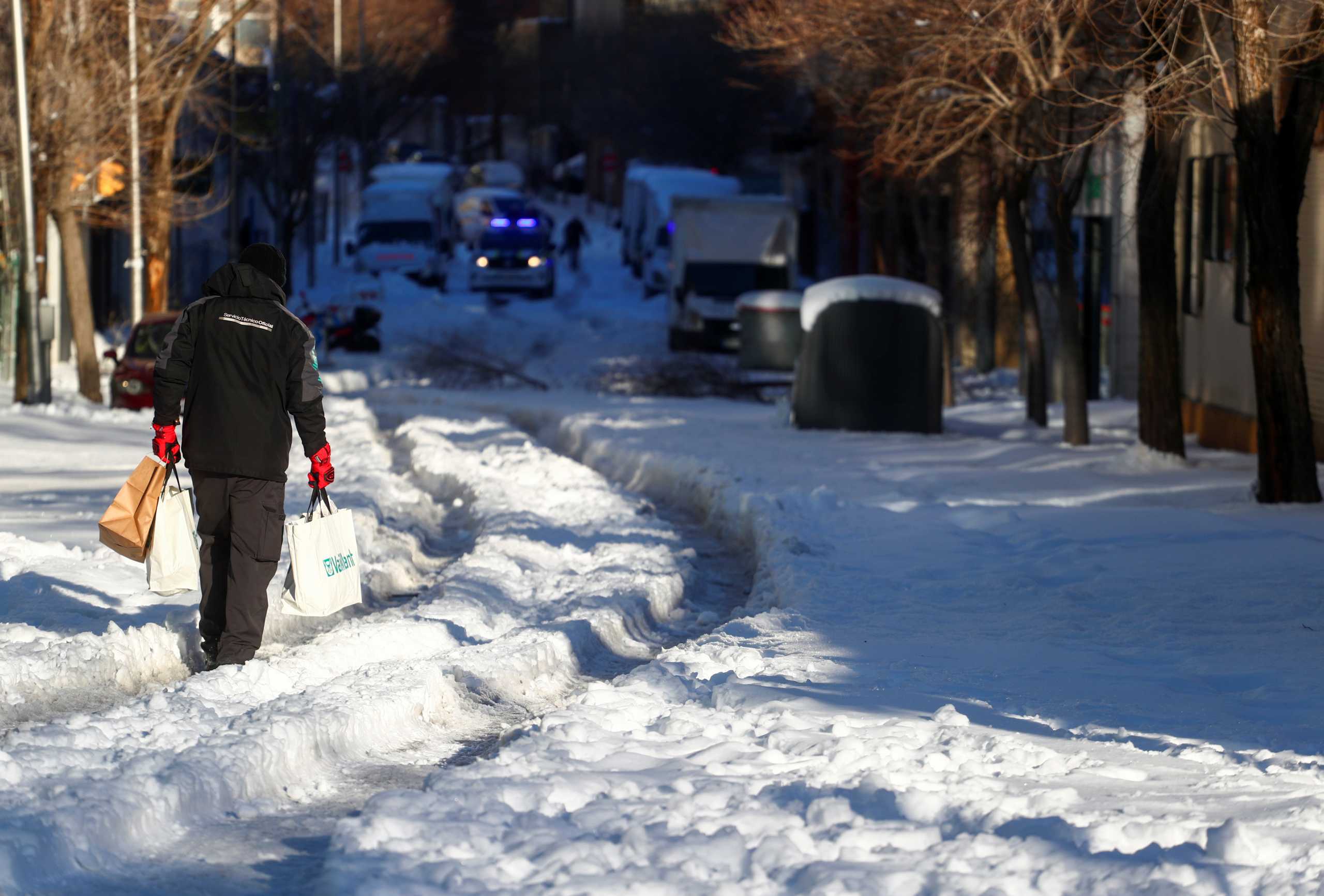 A person holding bags walks through a snow-covered street after heavy snowfall in Madrid, Spain, January 11, 2021. REUTERS