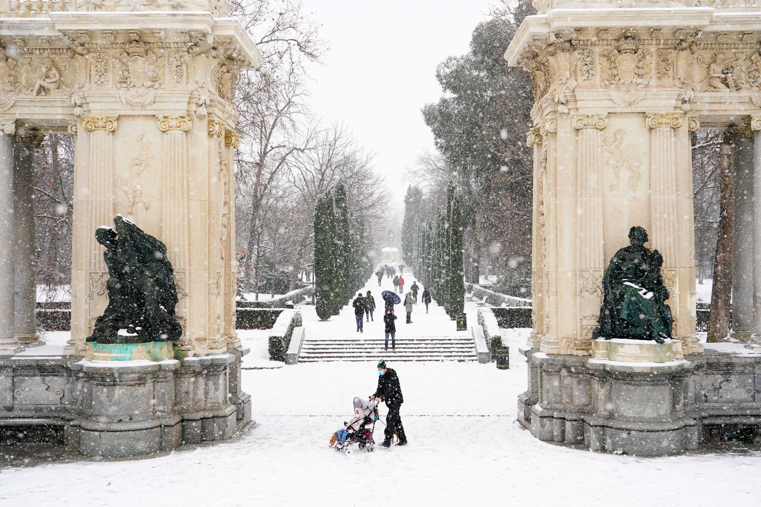 People walk during heavy snowfall in Retiro park in Madrid, Spain, January 8, 2021. REUTERS