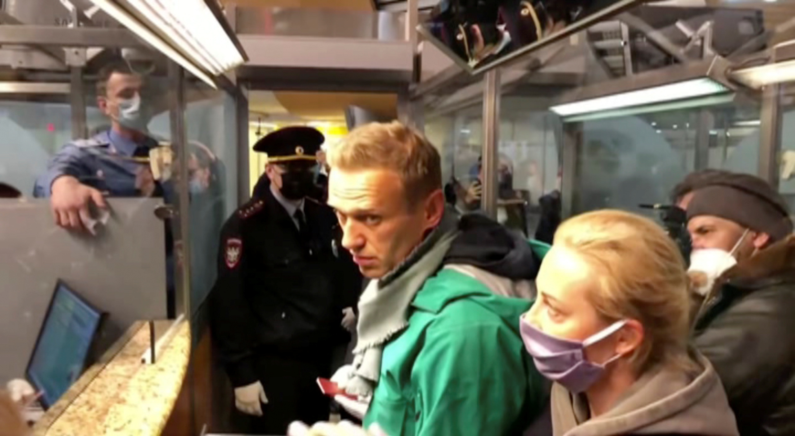 A still image taken from video footage shows law enforcement officers speaking with Russian opposition leader Alexei Navalny before leading him away at Sheremetyevo airport in Moscow, Russia January 17, 2021. REUTERS
