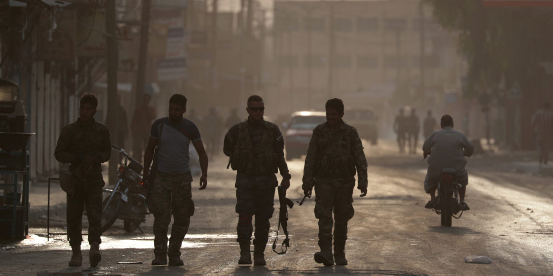 Turkey-backed Syrian rebel fighters walk together in the border town of Tal Abyad, Syria, October 15, 2019. REUTERS