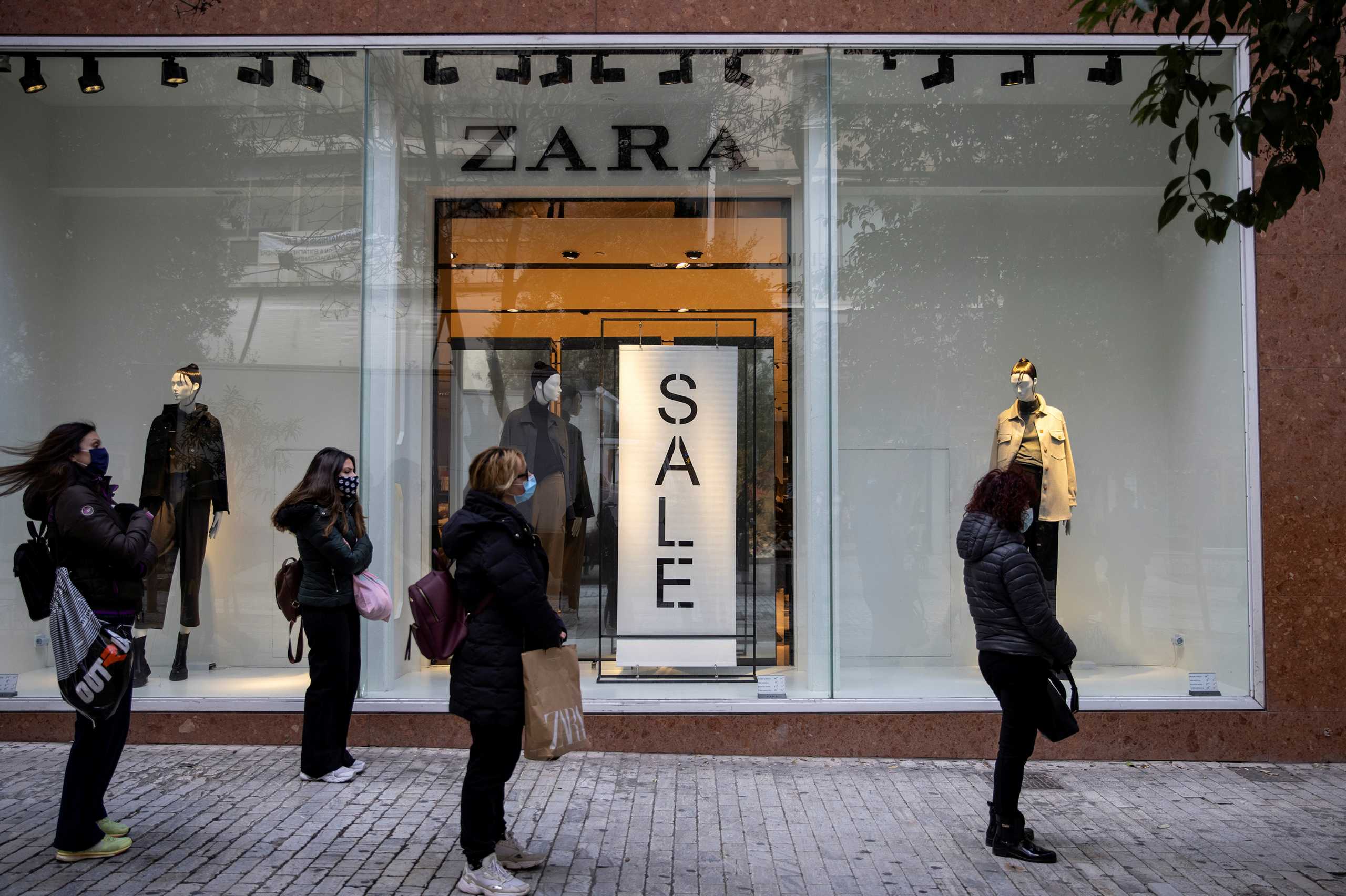 FILE PHOTO: People wearing protective face masks apply social distancing as they wait to enter a shop on the first day of the re-opening of retail stores, amid the coronavirus disease (COVID-19) pandemic, in Athens, Greece, January 18, 2021. REUTERS