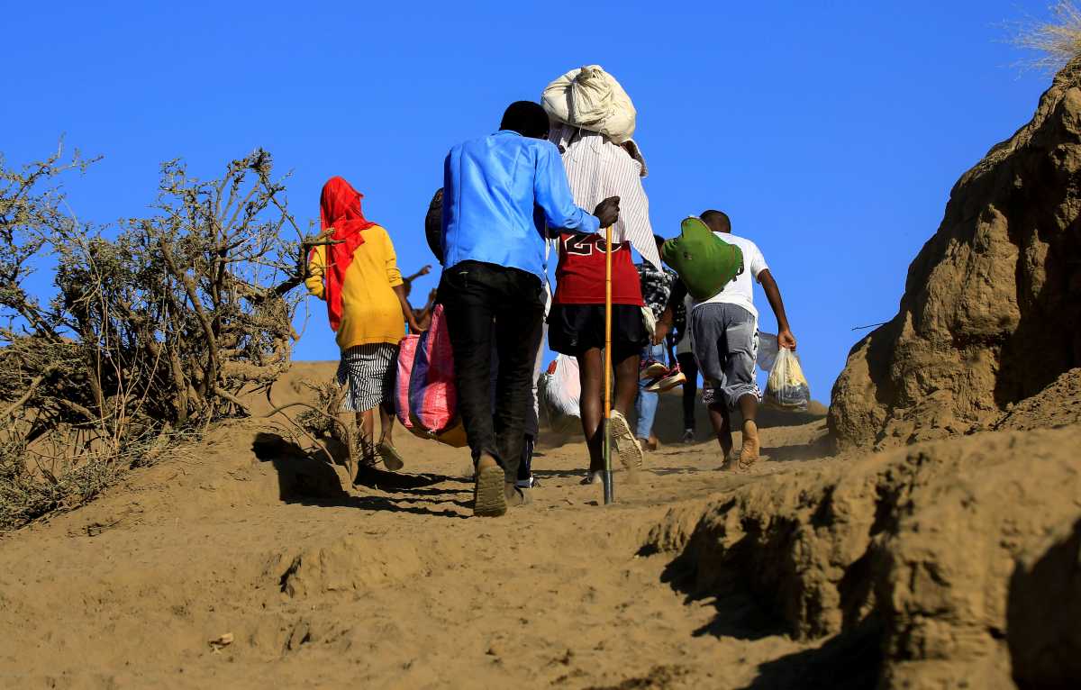 FILE PHOTO: Ethiopians, who fled the ongoing fighting in Tigray region, carry their belongings after crossing the Setit River on the Sudan-Ethiopia border, in the eastern Kassala state, Sudan December 16, 2020. REUTERS