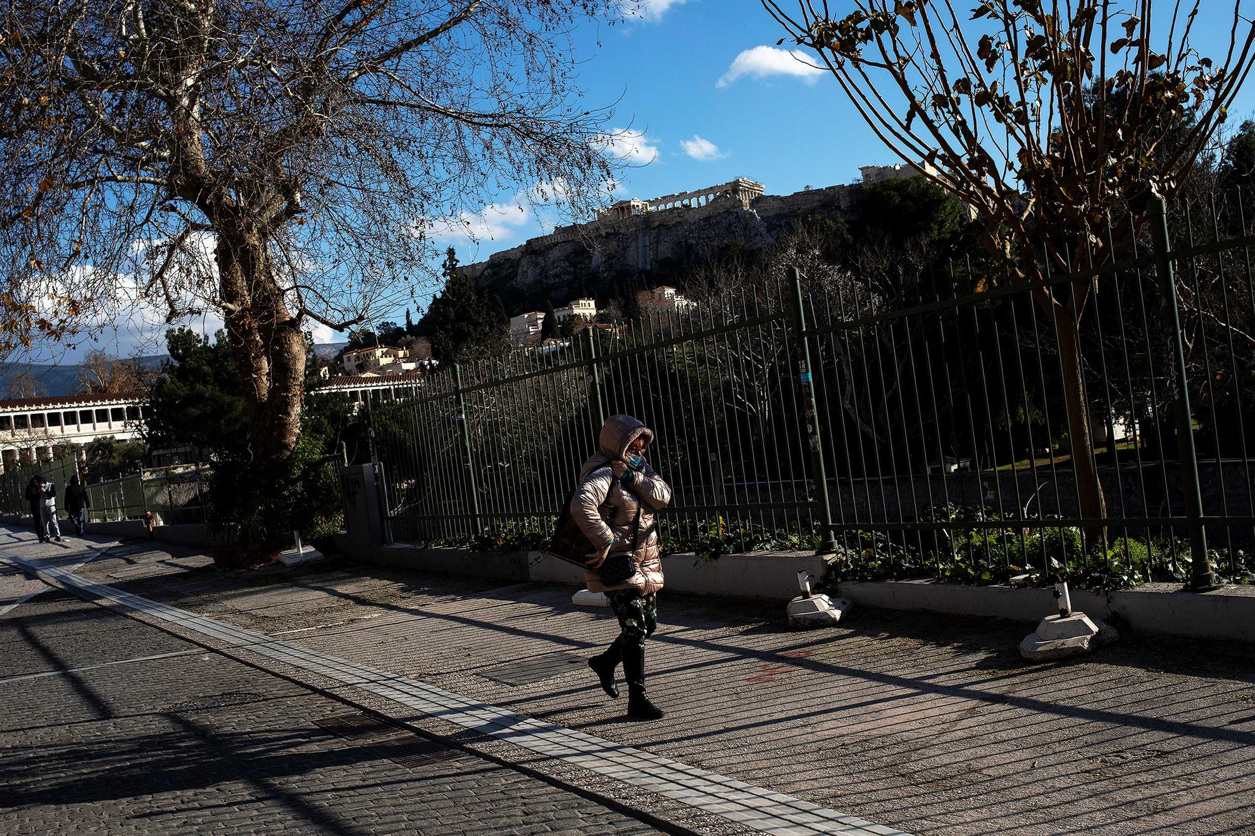 A woman wearing a protective face mask makes her way at the area of Thiseio, amid the coronavirus disease (COVID-19) outbreak, in Athens, Greece, January 27, 2021. REUTERS
