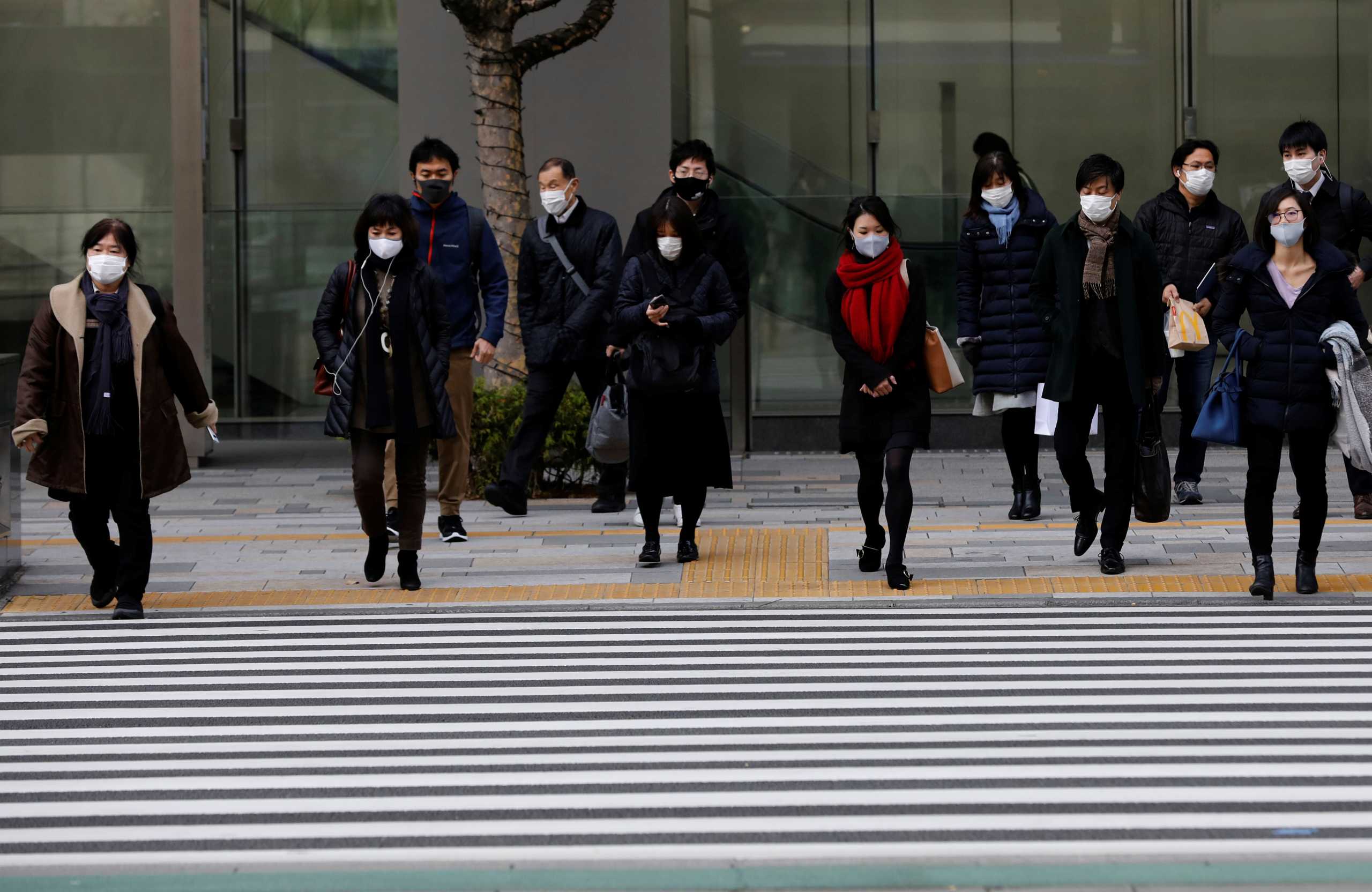 Pedestrians wearing protective masks following the coronavirus disease (COVID-19) outbreak, make their way on the first business day of the New Year in Tokyo, Japan, January 4, 2021. REUTERS