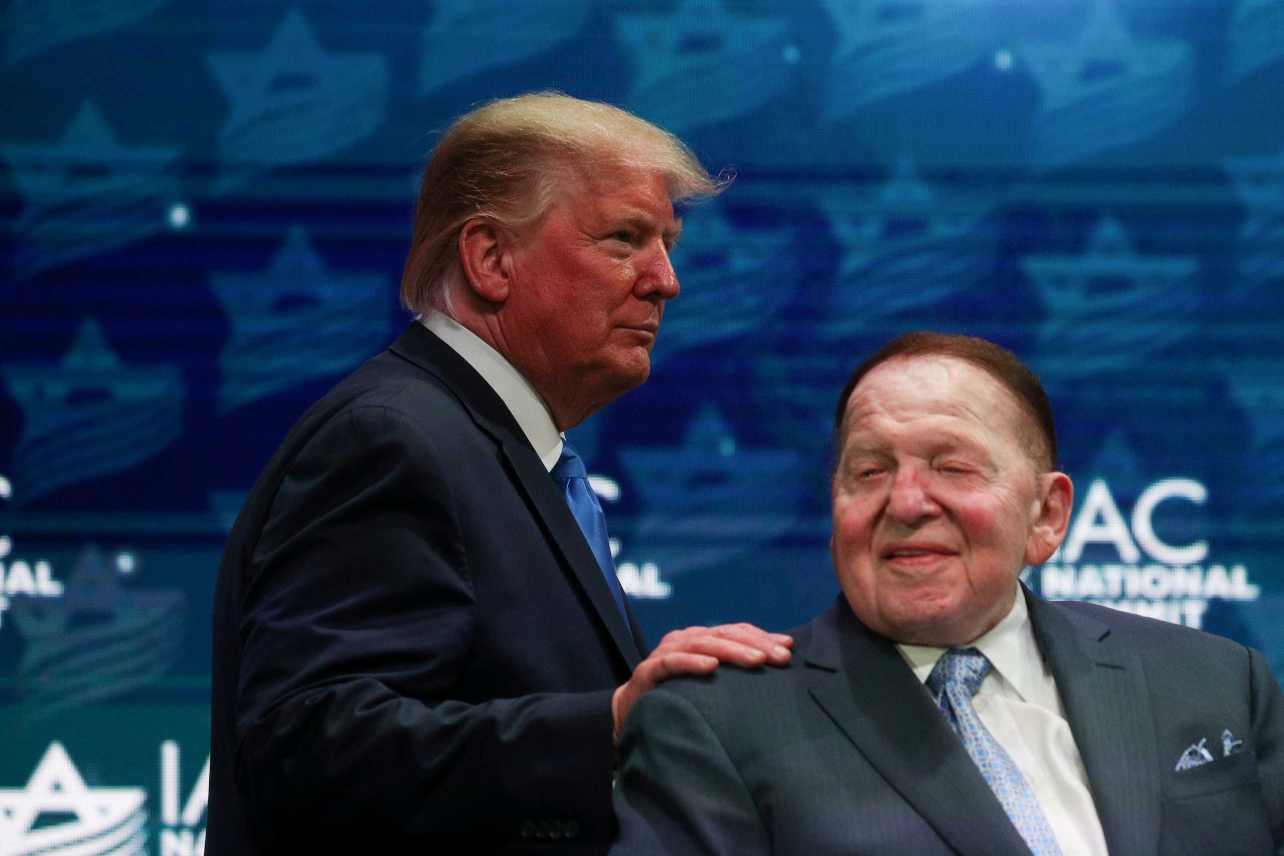 FILE PHOTO: U.S. President Donald Trump greets Sheldon Adelson while taking the stage at the Israeli American Council National Summit in Hollywood, Florida, U.S., December 7, 2019. REUTERS