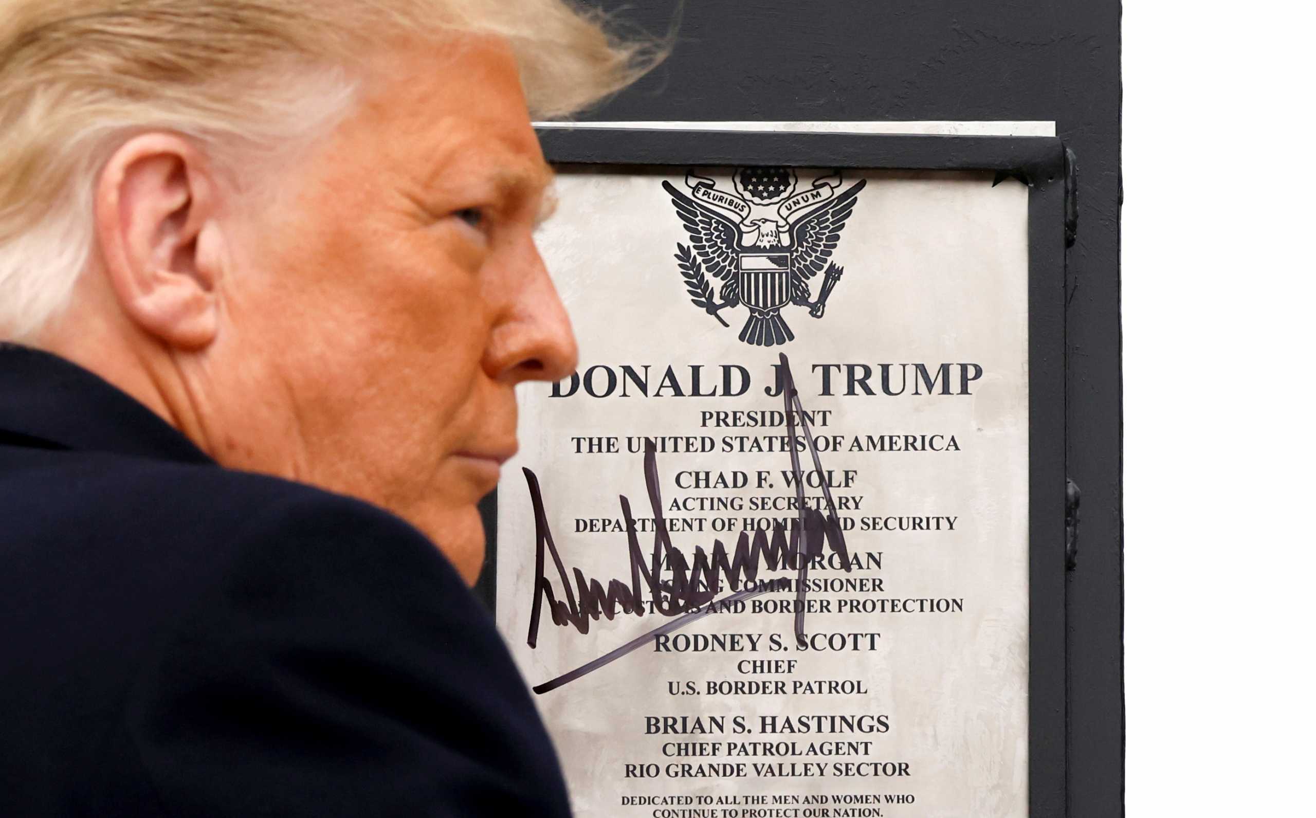 U.S. President Donald Trump signs a plaque placed at the U.S.-Mexico border wall during his visit, in Alamo, Texas, U.S., January 12, 2021. REUTERS