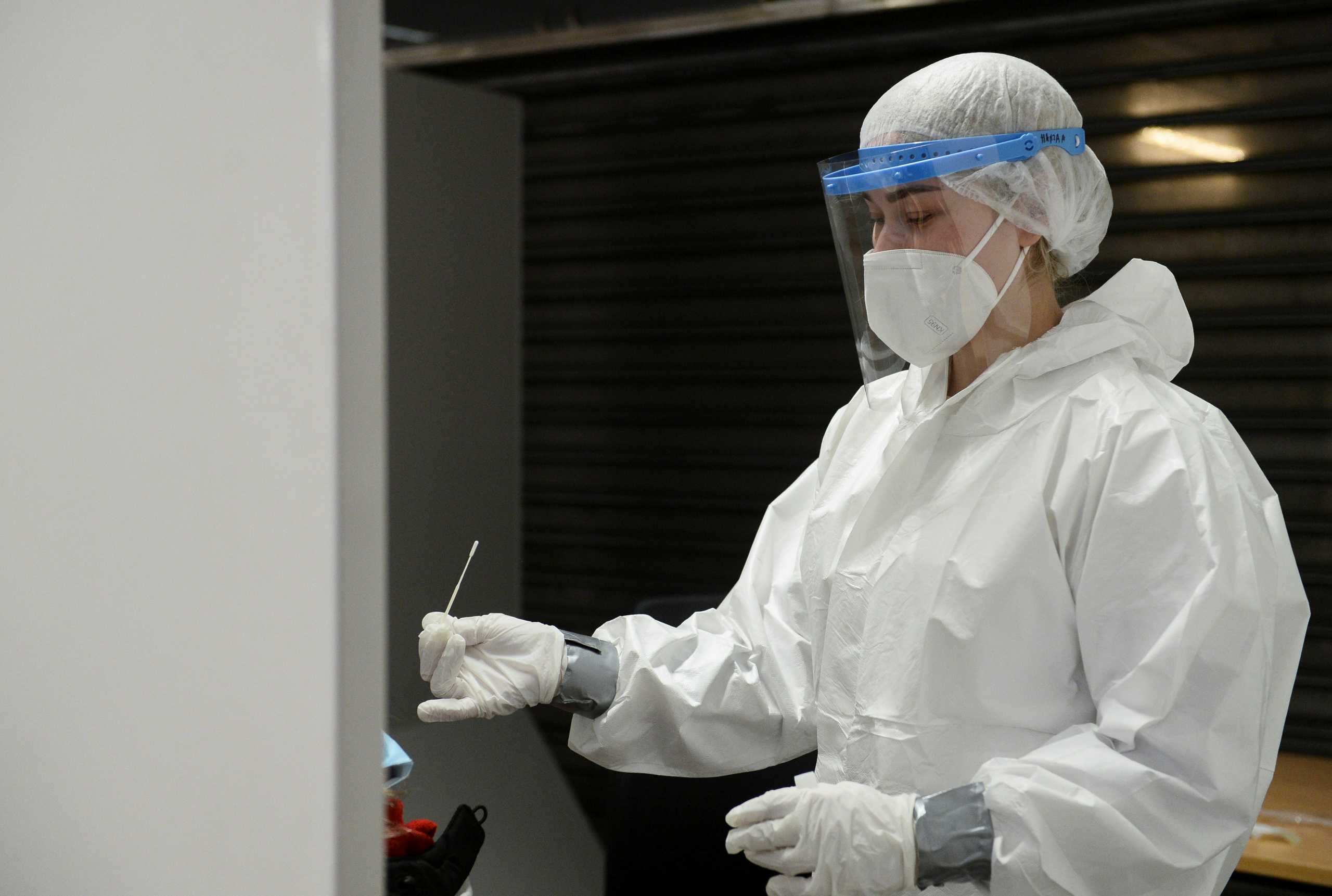 A healthcare worker holds a nasal swab sample at a new testing site at the Brussels Airport, Belgium January 2, 2021. REUTERS
