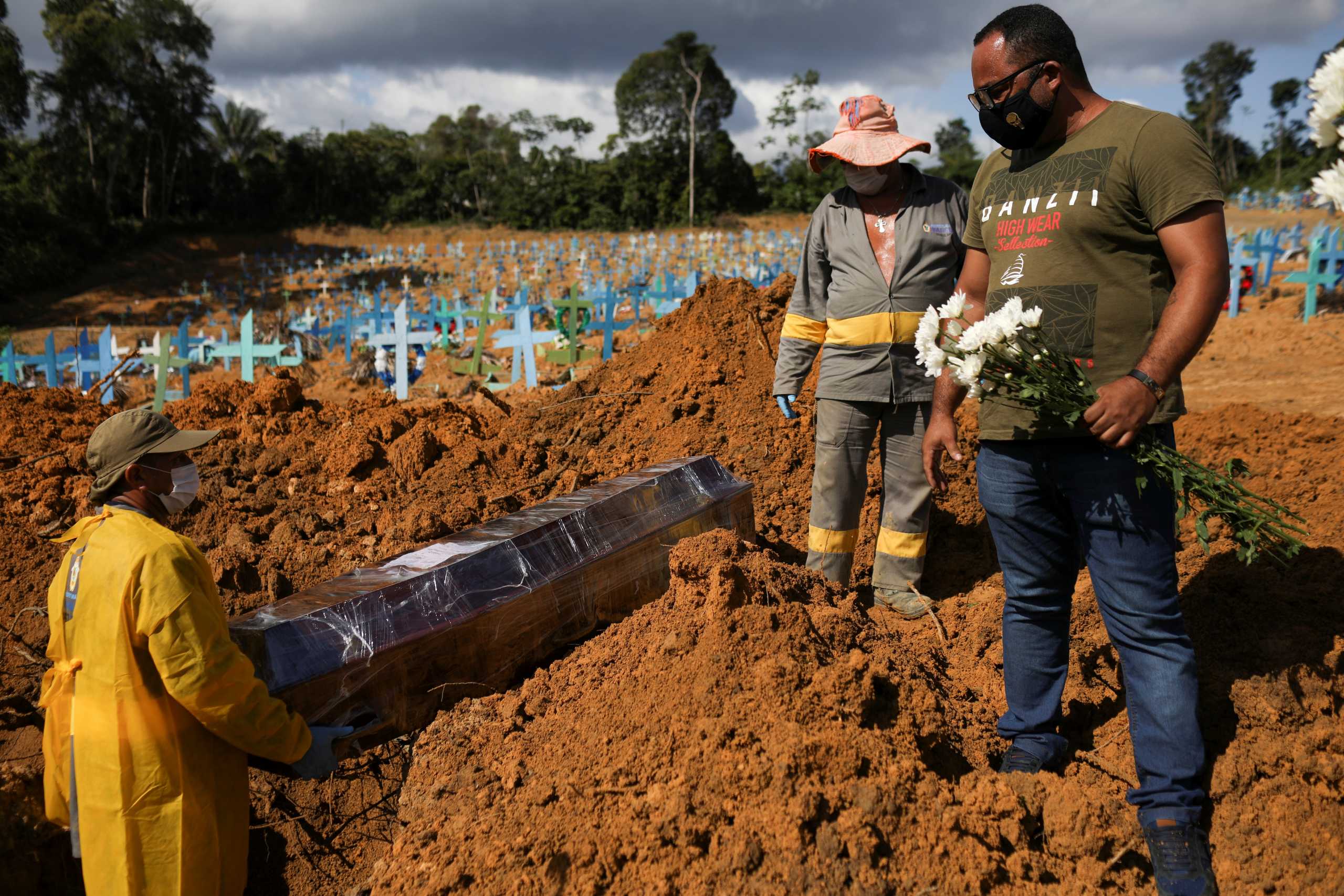 A son of Veronica Ferreira, 73, who passed away due to the coronavirus disease (COVID-19), stands next to her grave during the burial at the Parque Taruma cemetery in Manaus, Brazil, December 31, 2020. REUTERS
