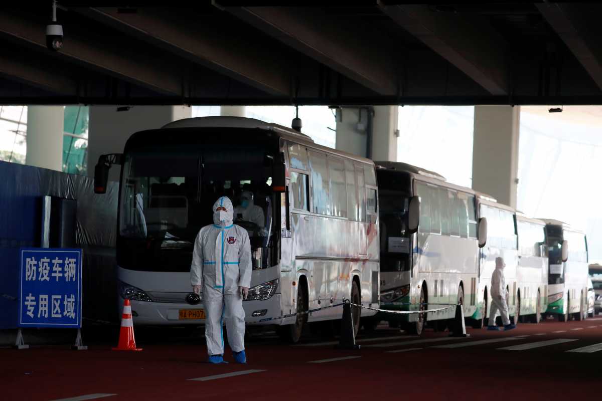 A staff member in protective suit stands next to buses before the expected arrival of a World Health Organisation (WHO) team tasked with investigating the origins of the coronavirus disease (COVID-19) pandemic, at Wuhan Tianhe International Airport in Wuhan, Hubei province, China January 14, 2021. REUTERS
