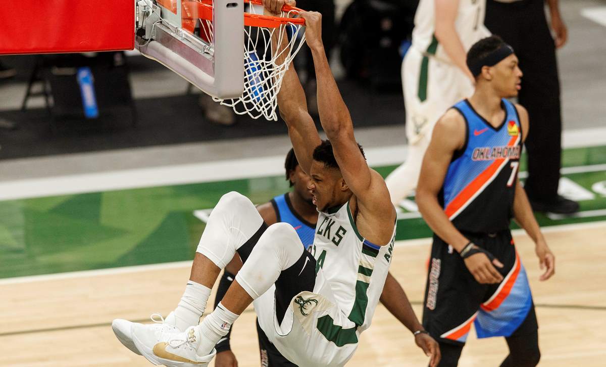 Feb 19, 2021; Milwaukee, Wisconsin, USA;  Milwaukee Bucks forward Giannis Antetokounmpo (34) hangs from the rim following a dunk during the third quarter against the Oklahoma City Thunder at Fiserv Forum. Mandatory Credit: Jeff Hanisch-USA TODAY Sports