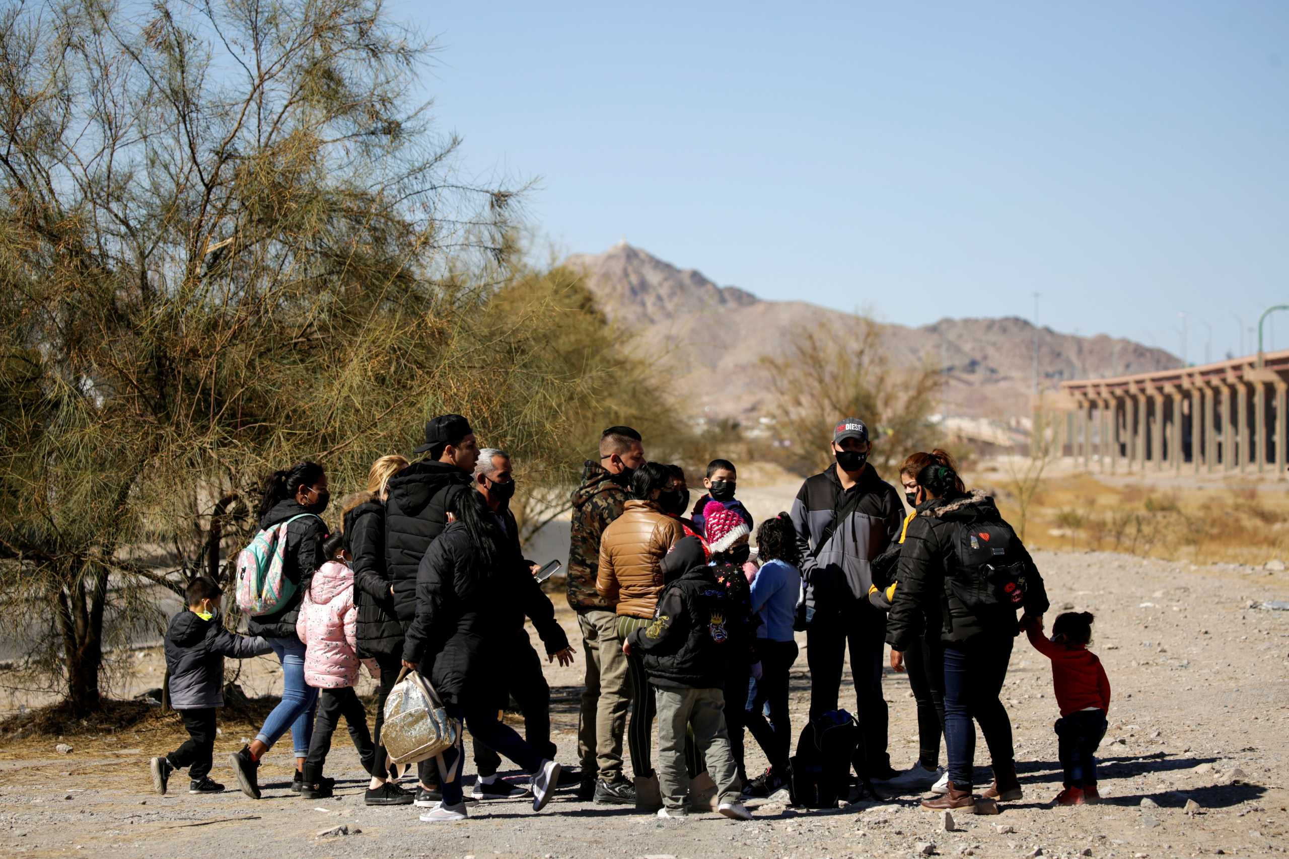 FILE PHOTO: Migrants stand near the Rio Bravo river before crossing it to turn themselves in to request for asylum in El Paso, Texas, U.S., in Ciudad Juarez, Mexico February 5, 2021. REUTERS