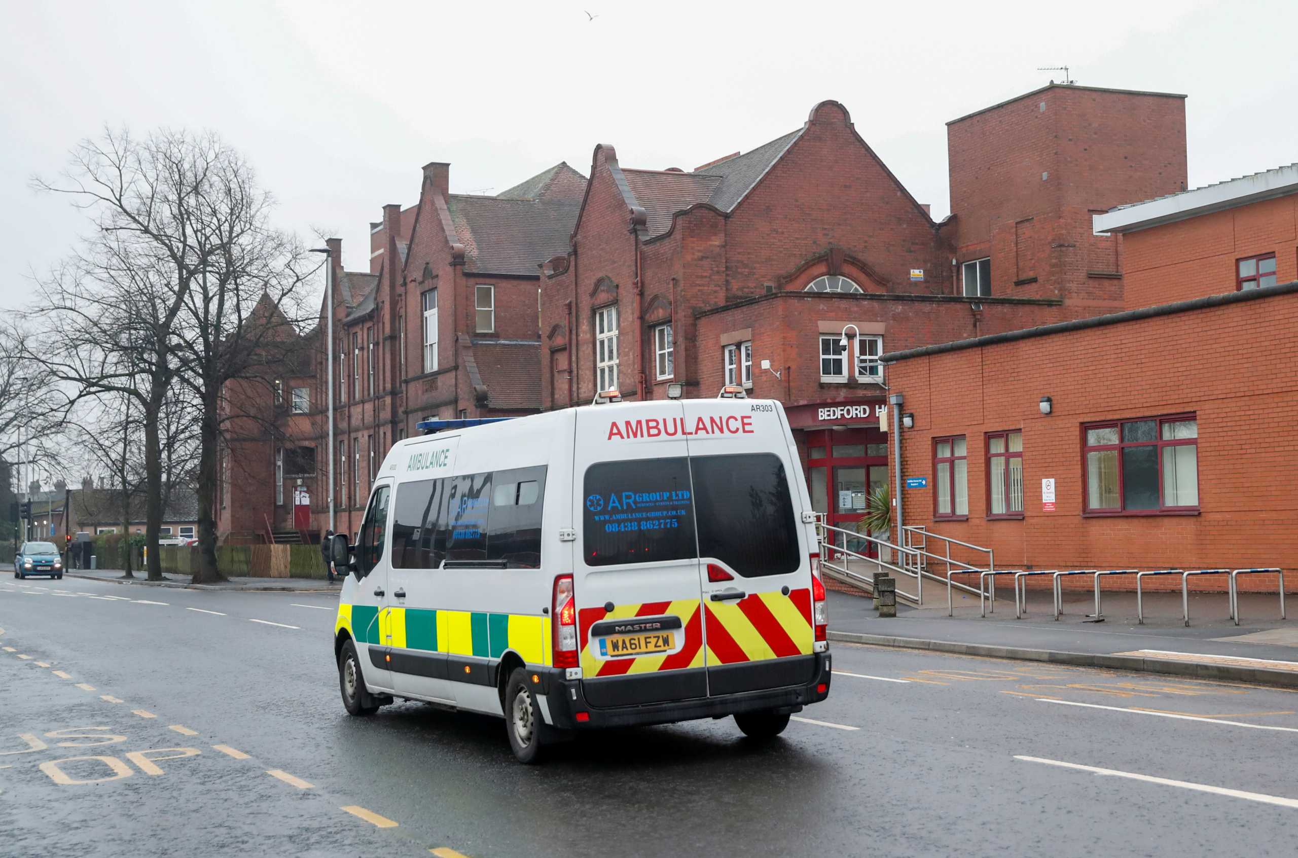 An ambulance rides in front of Bedford Hospital as Britain's centenarian fundraiser Captain Sir Tom Moore is taken to a hospital after testing positive for coronavirus disease (COVID-19) during treatment for pneumonia, in Bedford, Britain, February 1, 2021. REUTERS
