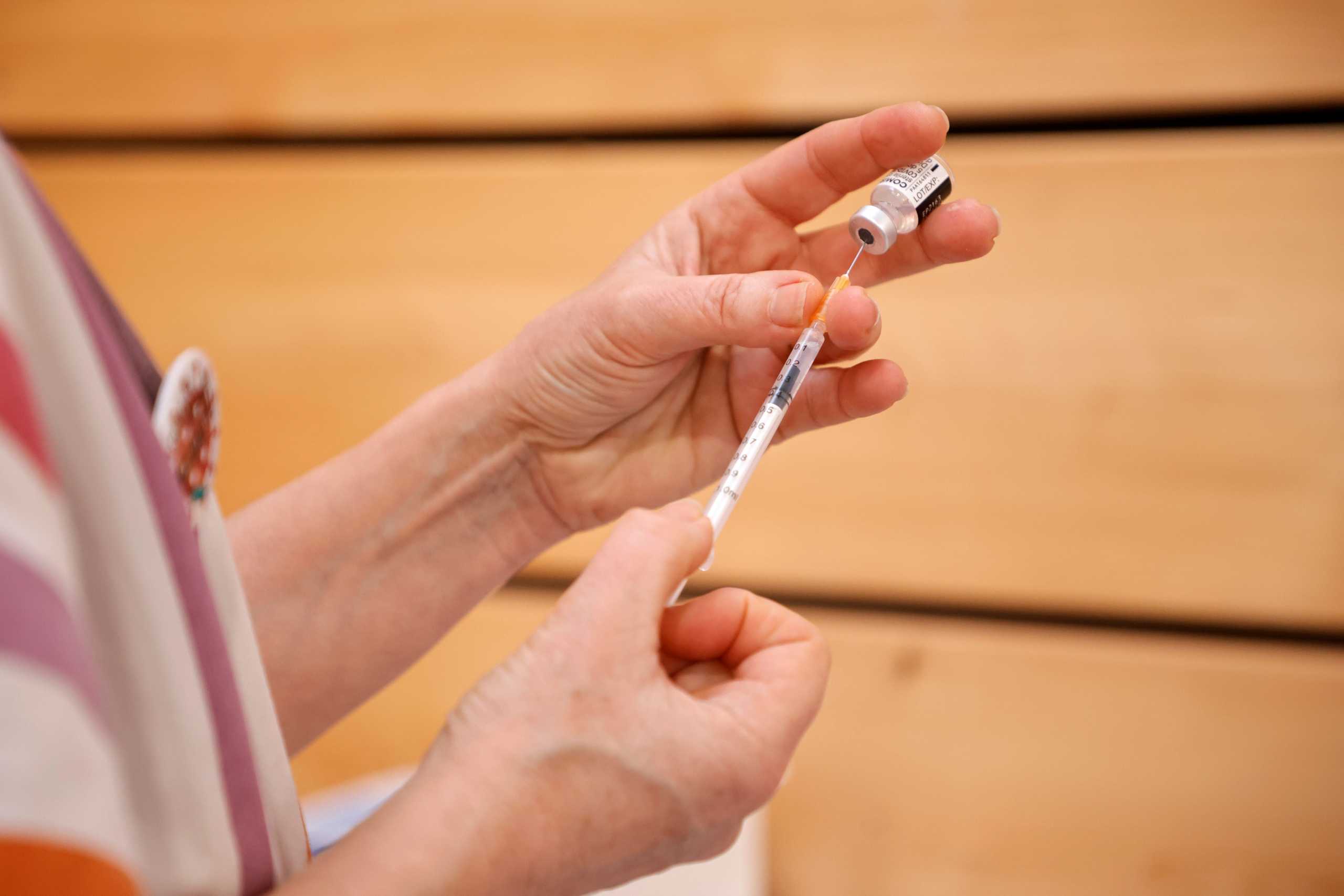 A medical worker prepares a syringe with a dose of the "Comirnaty" Pfizer-BioNTech COVID-19 vaccine at a coronavirus disease (COVID-19) vaccination center installed inside a gymnasium in Taverny near Paris as the spread of the coronavirus disease (COVID-19) was worrying in 20 French departments including Paris and the surrounding region, France, February 26, 2021. REUTERS