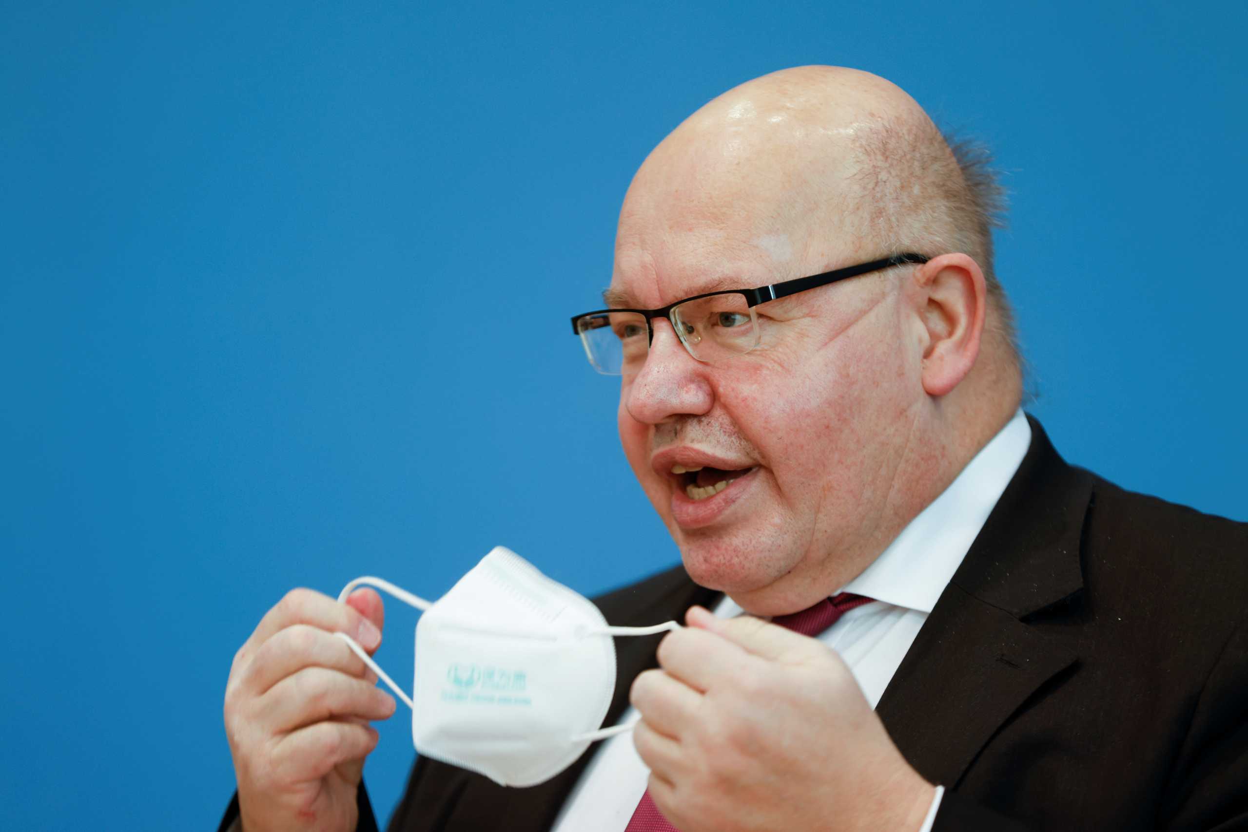 Germany's Economy Minister Peter Altmaier removes his face mask as he arrives for a news conference on the annual economic report in Berlin, Germany January 27, 2021. Odd Andersen
