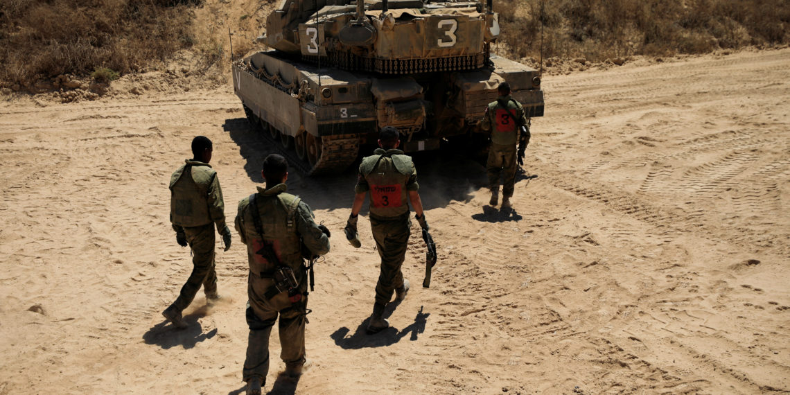 Israeli soldiers walk by a tank near the border between Israel and the Gaza Strip August 16, 2020. REUTERS
